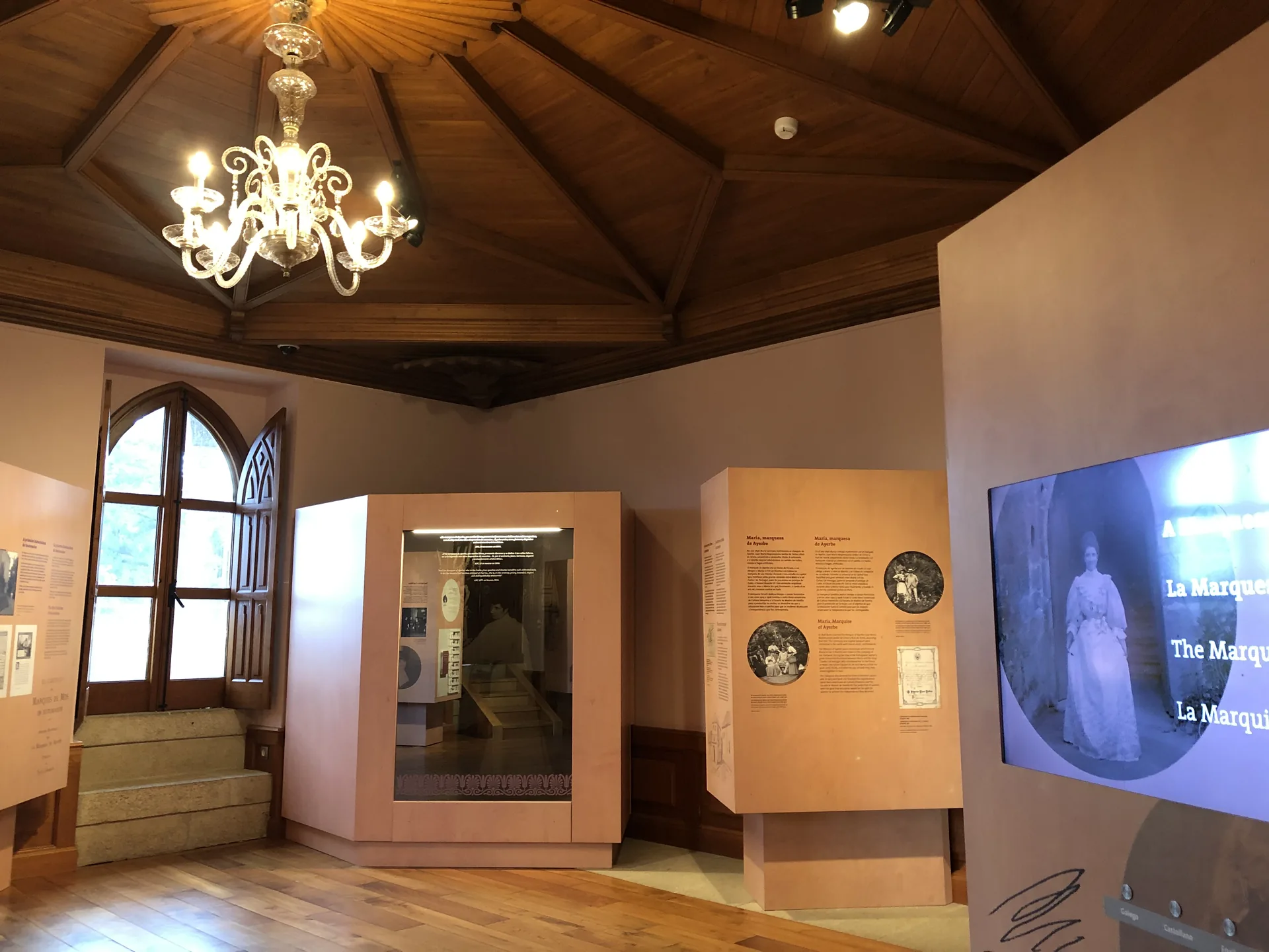 Sala de exposição dedicada a María Vinyals no interior do Castelo de Soutomaior, com painéis históricos e lustre.