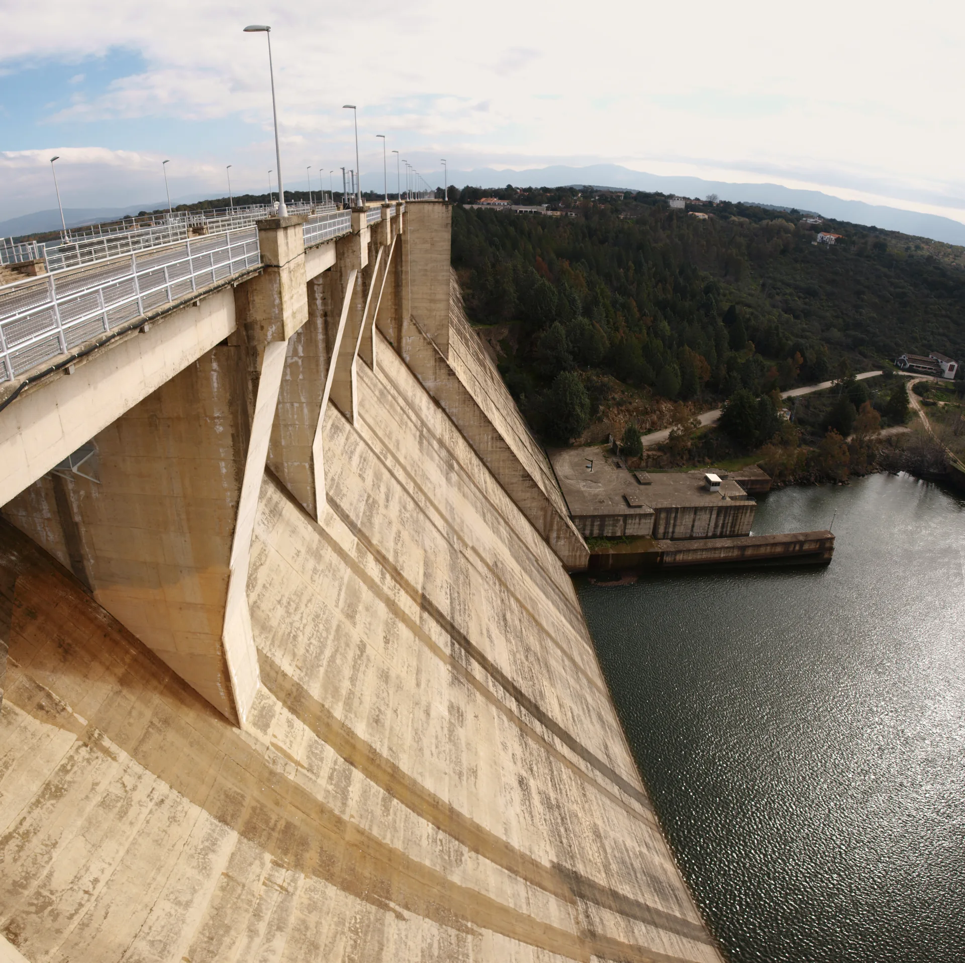Barragem do reservatório Gabriel y Galán, com a água represada e as montanhas ao fundo, em Guijo de Granadilla.