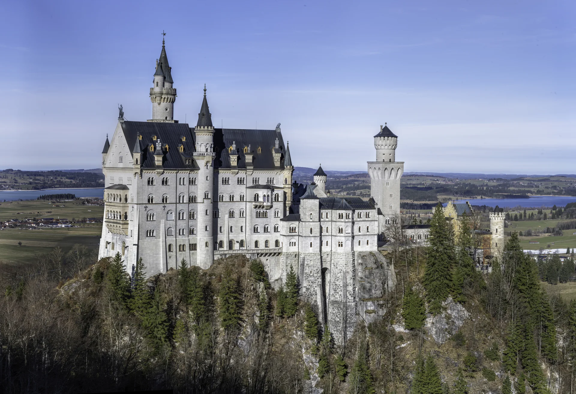 Castelo de Neuschwanstein visto do exterior entre montanhas e árvores da Baviera