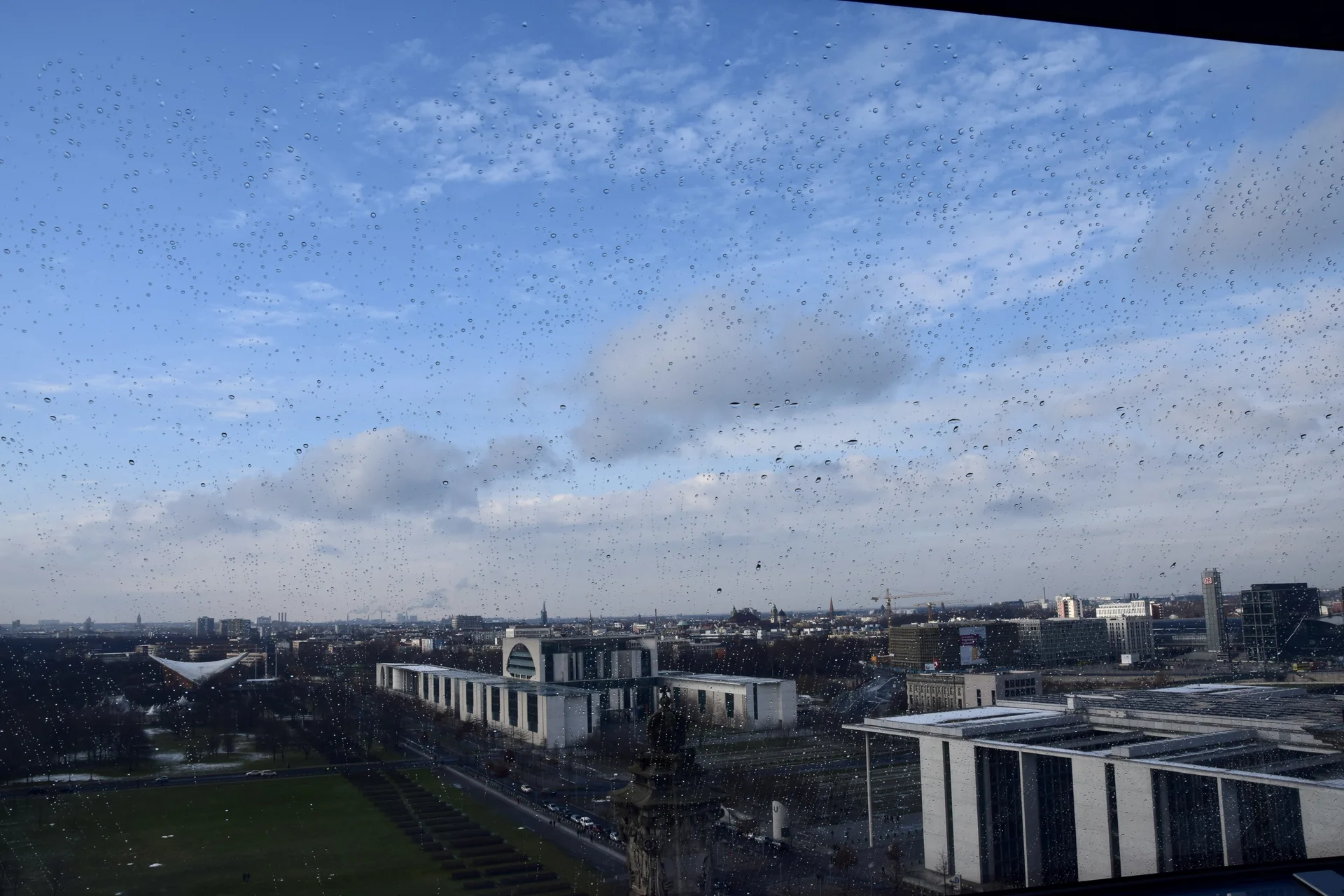 Vista da paisagem urbana de Berlim através da cúpula de vidro do Reichstag, com gotas de chuva no vidro.