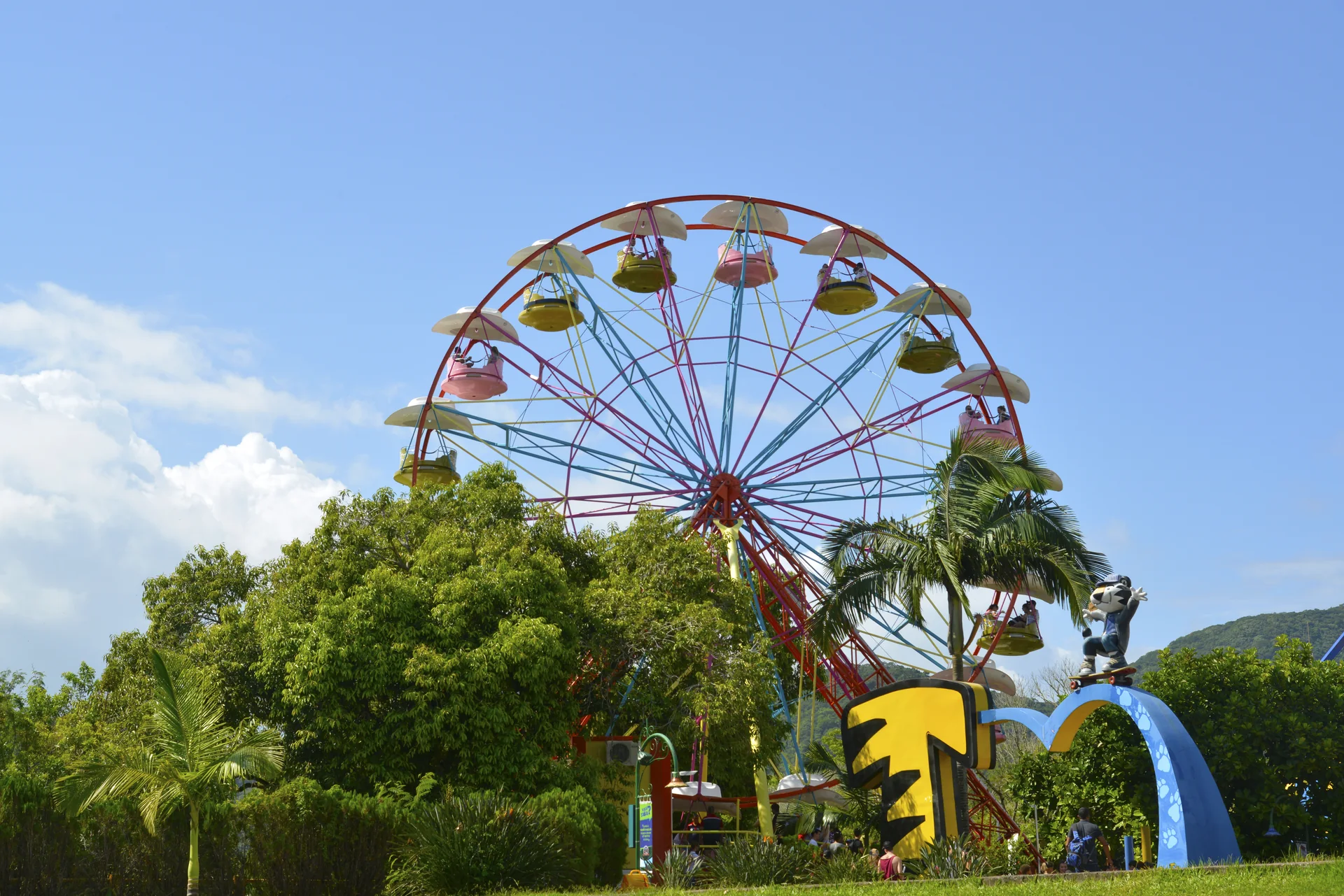 Roda-gigante e paisagismo em área do Beto Carrero World, sob céu azul