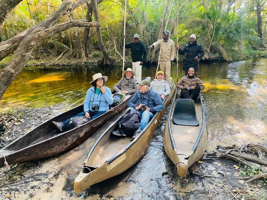 Mokoros atracados em um canal arborizado do Delta do Okavango, com guias e visitantes