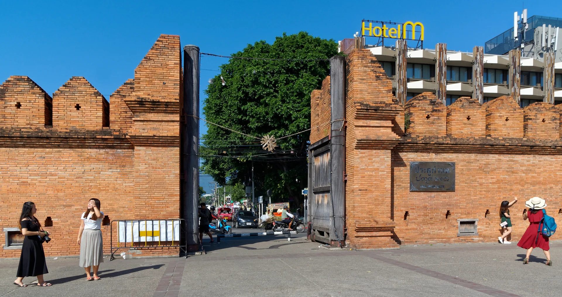 Portão Tha Phae, na muralha histórica da cidade antiga de Chiang Mai, com pedestres na praça.