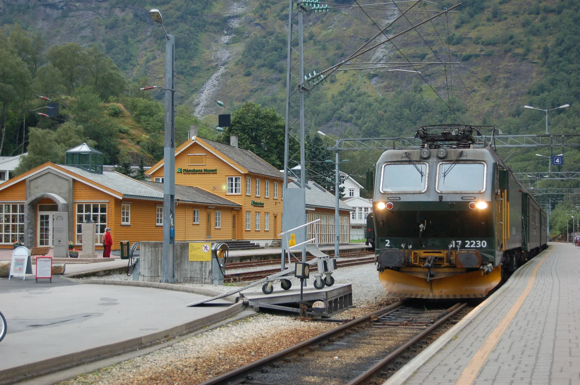 Trem da Flåmsbana parado na estação de Flåm, diante das montanhas da Noruega ocidental.