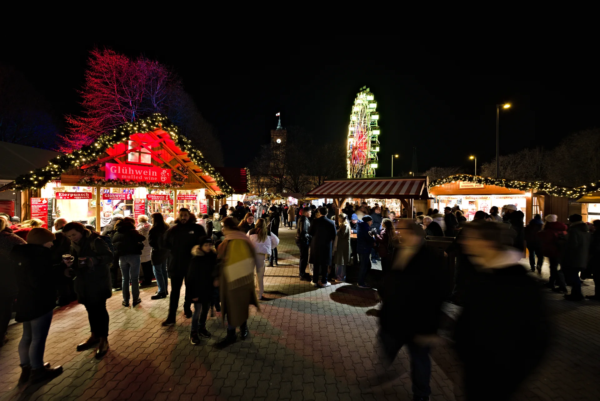 Mercado de Natal diante da Prefeitura Vermelha, em Berlim, iluminado ao anoitecer.