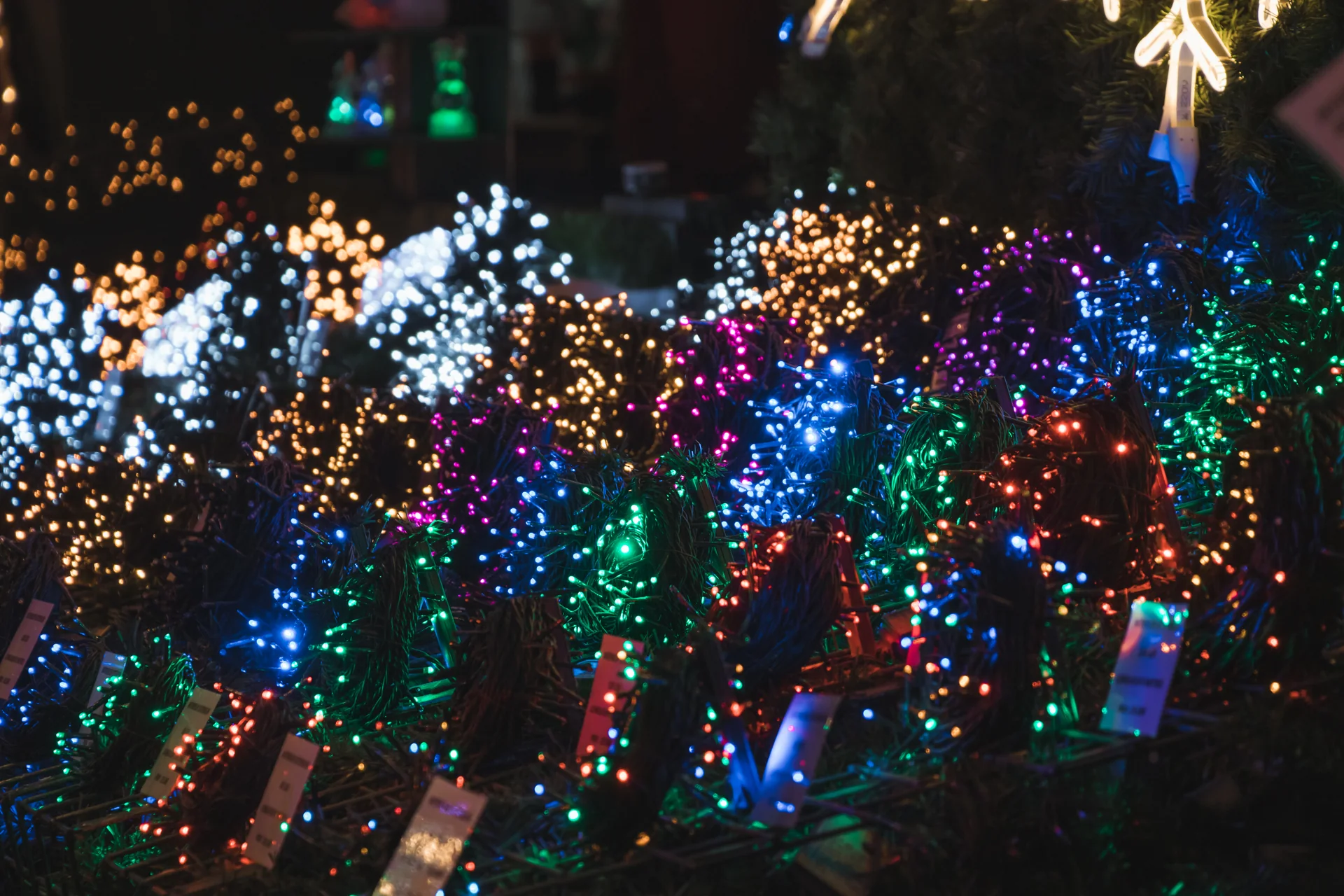 Cordões de luz colorida em primeiro plano no mercado de Natal de Estrasburgo à noite.