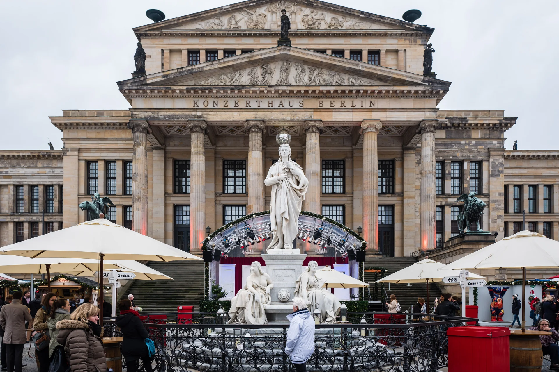 Mercado de Natal no Gendarmenmarkt de Berlim diante da fachada do Konzerthaus, com visitantes e bancas na praça.