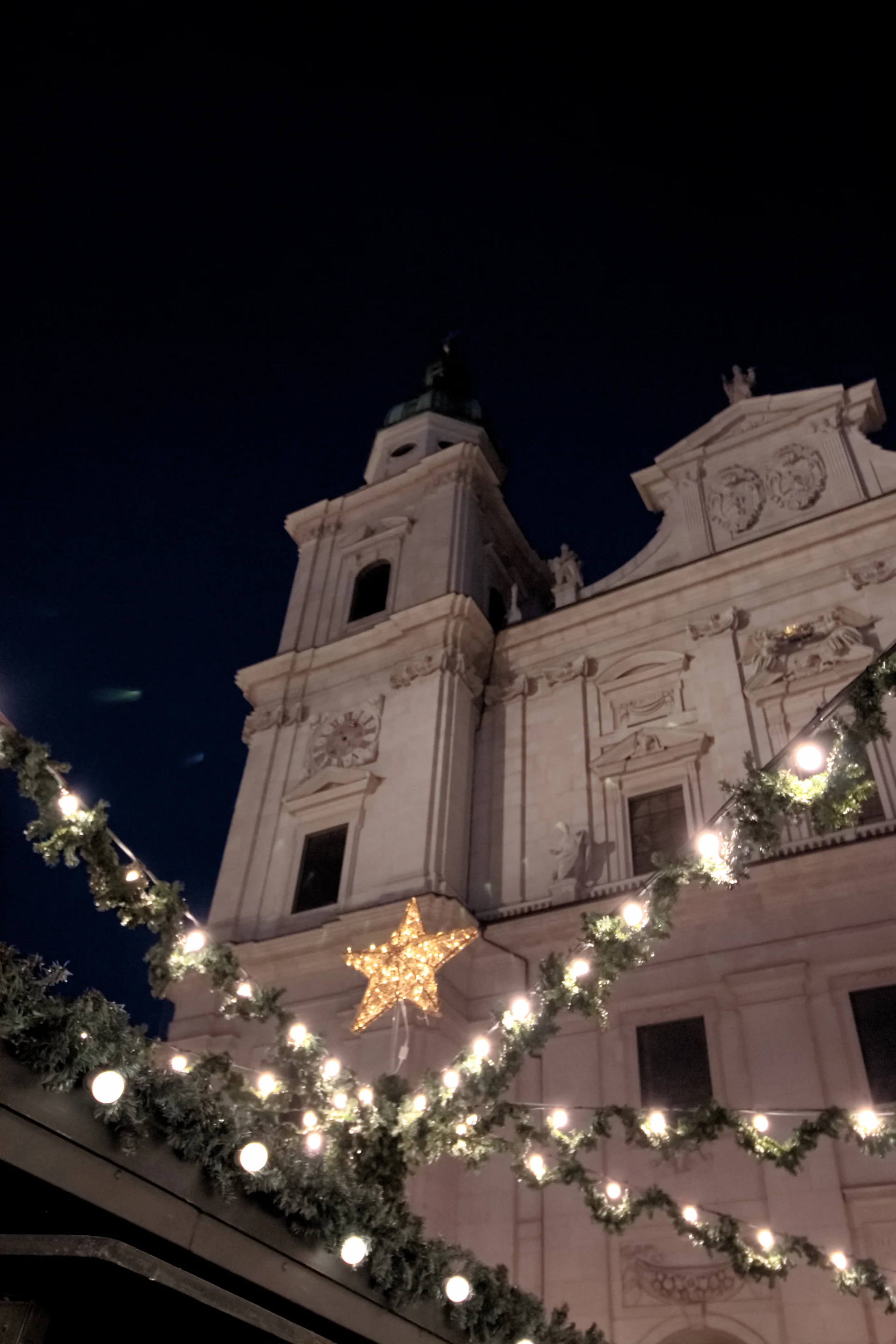 Catedral de Salzburgo vista à noite acima de iluminação e guirlandas do Christkindlmarkt na Domplatz.