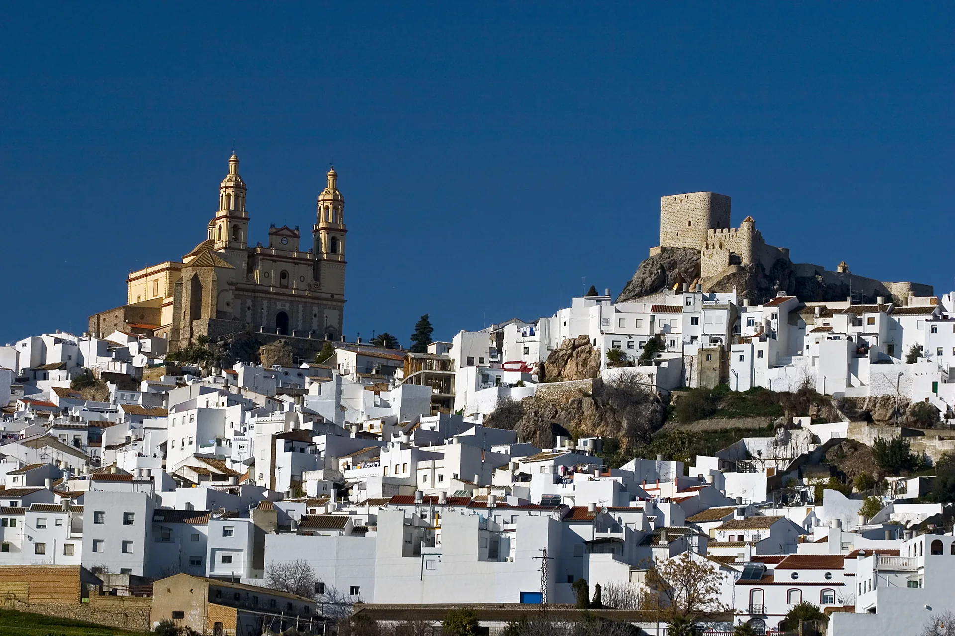 Igreja de Nuestra Señora de la Encarnación e Castelo de Olvera acima do casario branco.