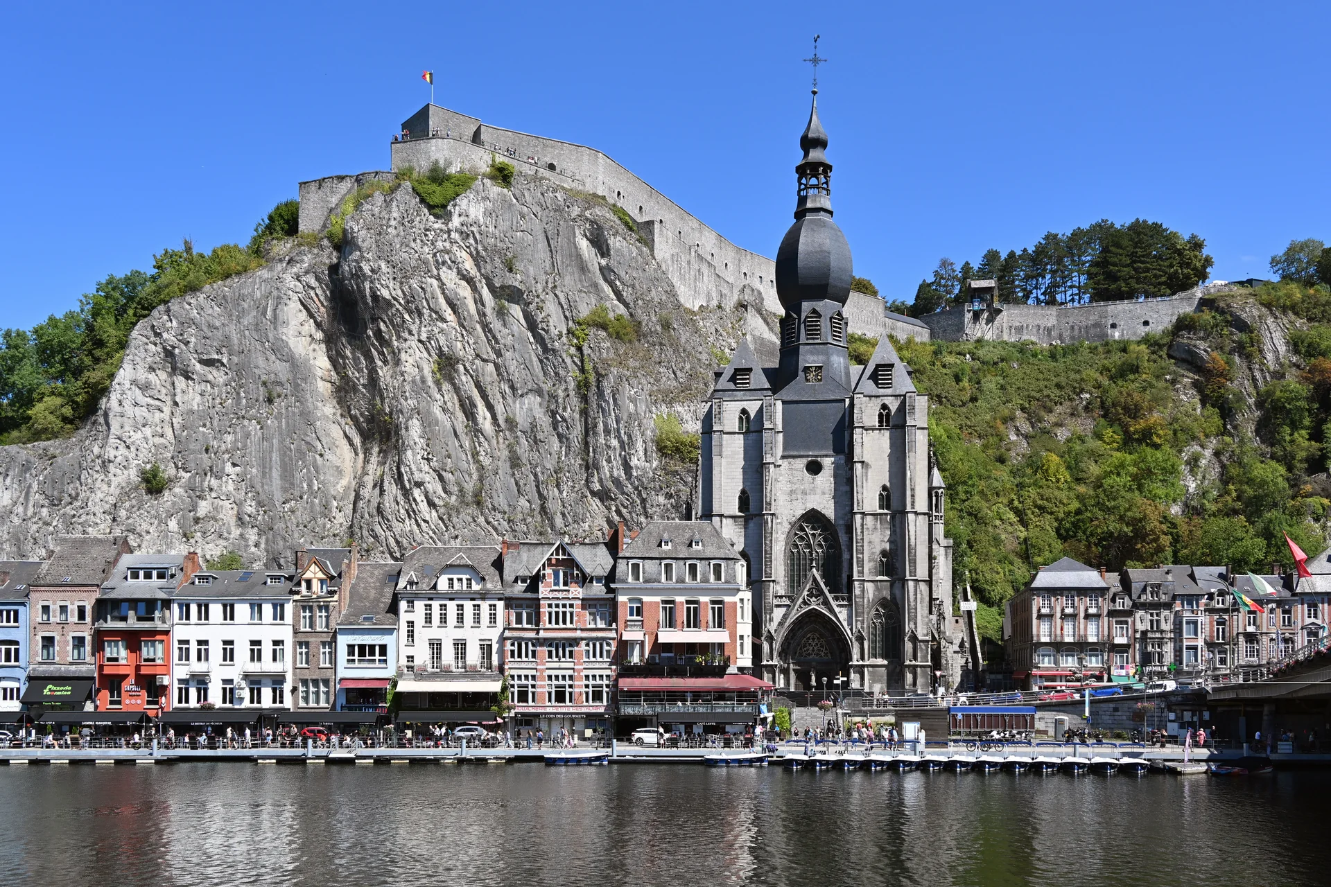 Vista de Dinant com a colegiada Notre-Dame, a cidadela no rochedo, casario à margem e o rio Mosa.