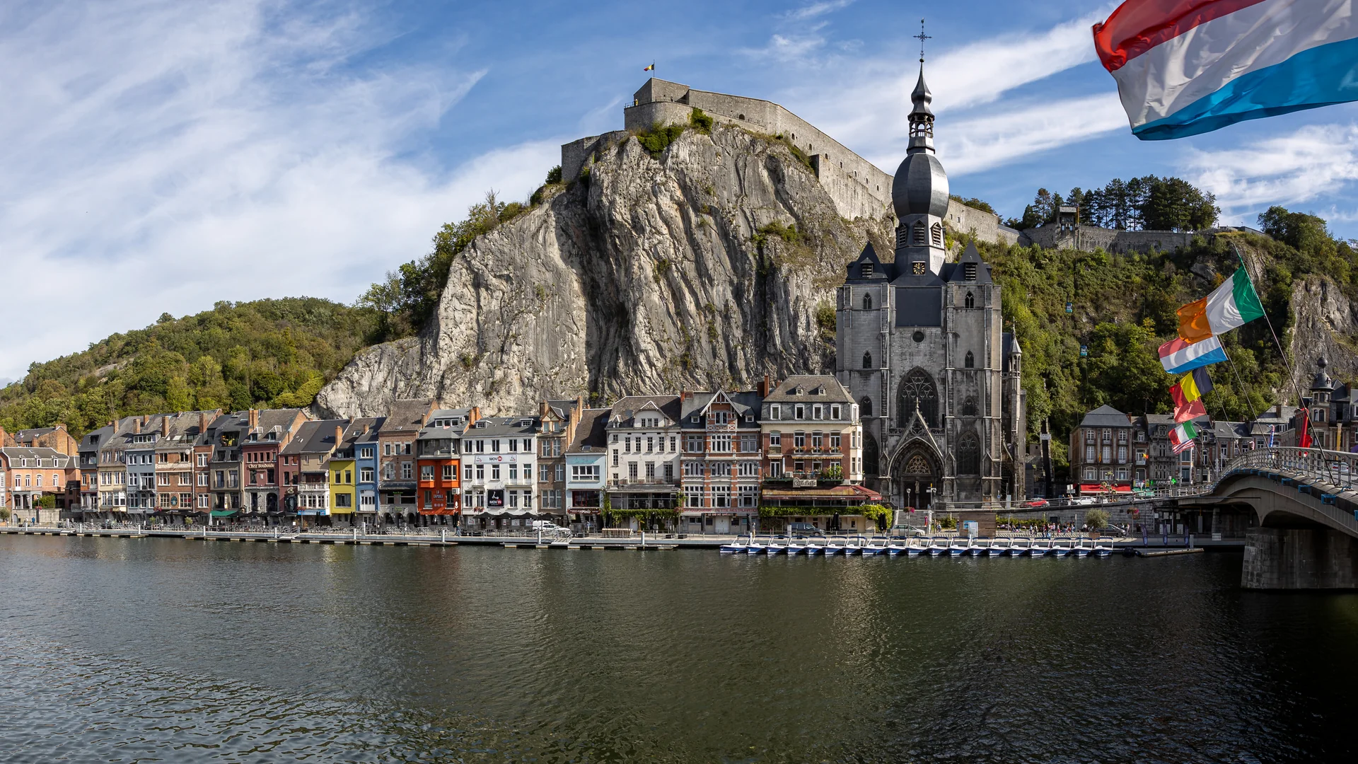 Panorama de Dinant com o rio Mosa, a colegiada Notre-Dame, casario e a cidadela no alto do rochedo.