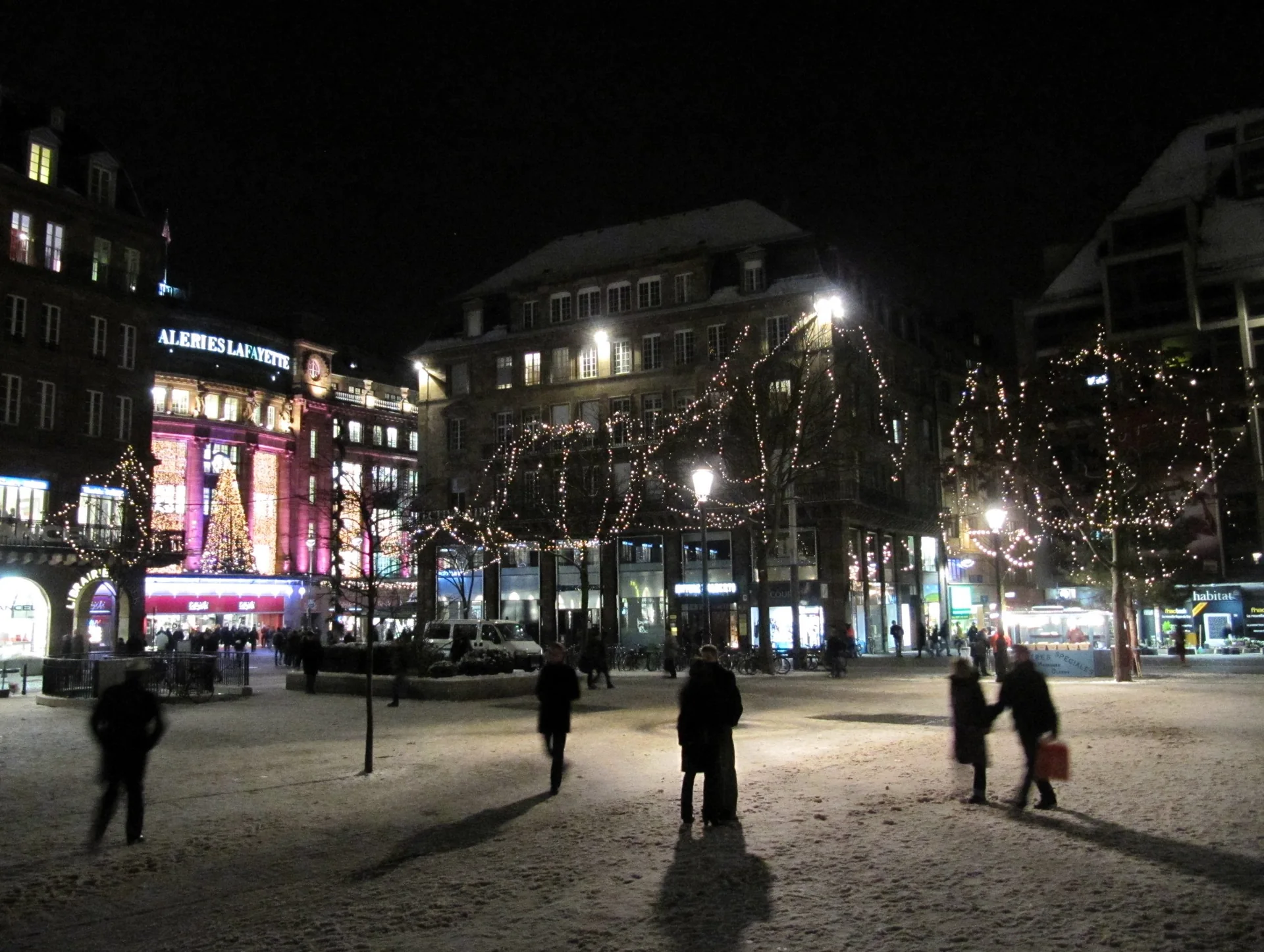 Praça Kléber em Estrasburgo à noite, com iluminação natalina e pedestres no inverno