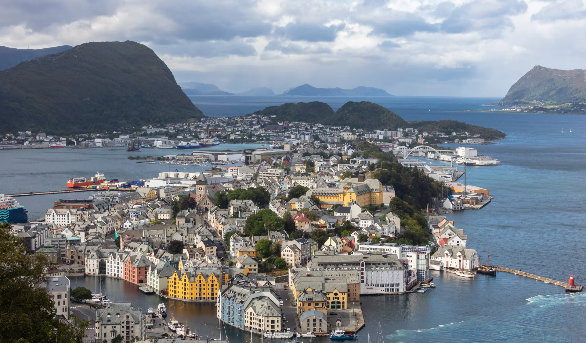 Centro e porto de Ålesund vistos da montanha Aksla, com ilhas e mar ao fundo.