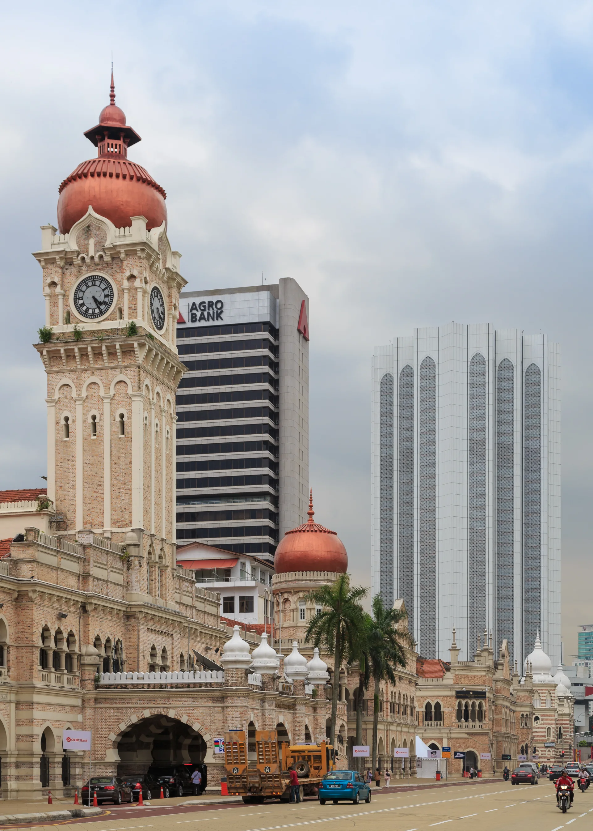 Fachada do edifício Sultan Abdul Samad em Kuala Lumpur, com torre do relógio e torres urbanas ao fundo.