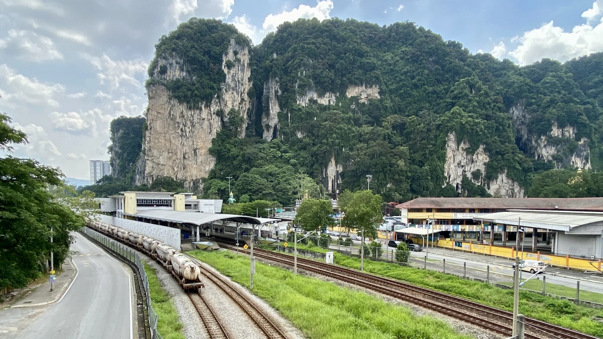 Afloramento calcário de Batu Caves visto da estação ferroviária, sob céu claro.