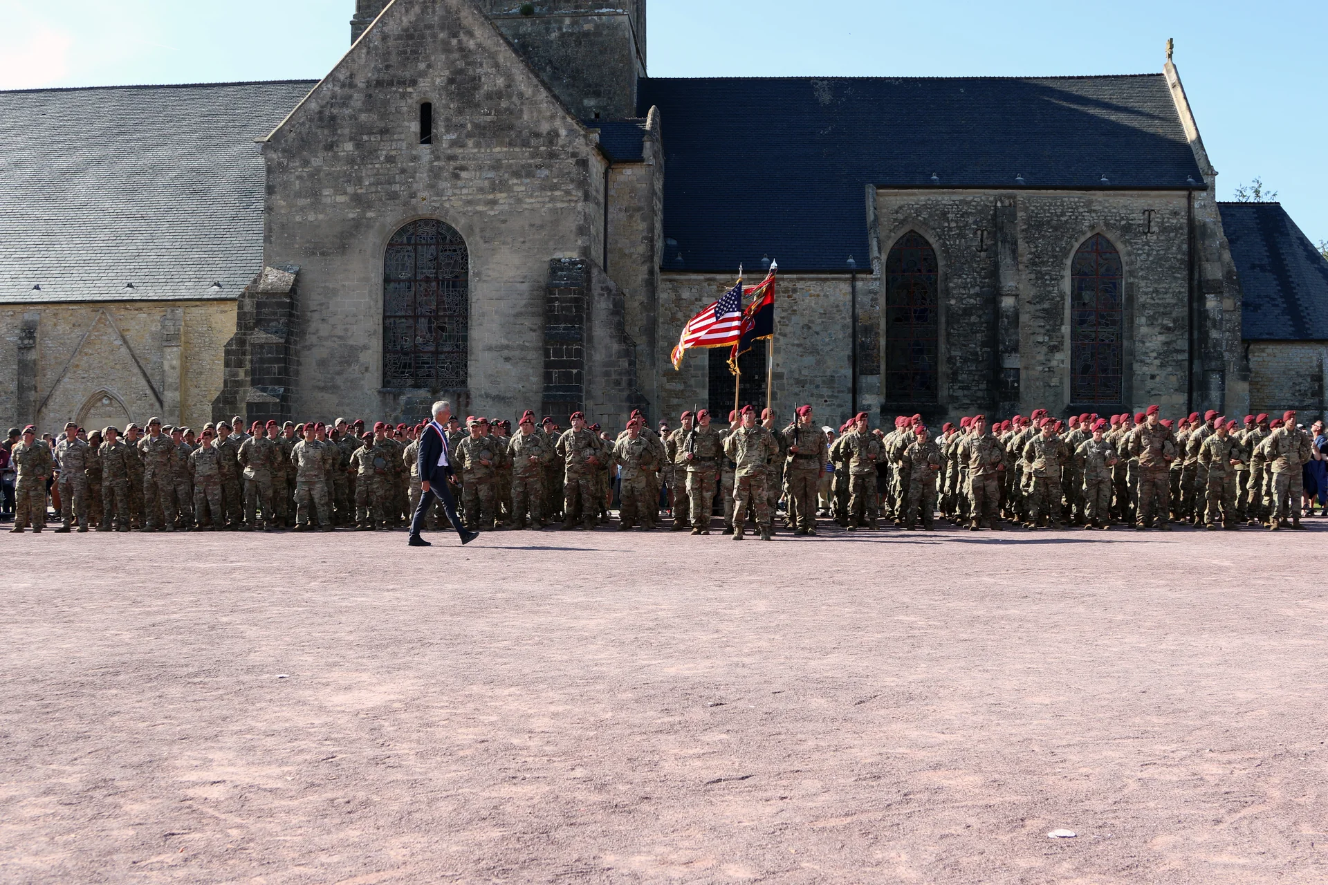 Igreja de Sainte-Mère-Église durante cerimônia com militares reunidos diante do edifício, na Normandia