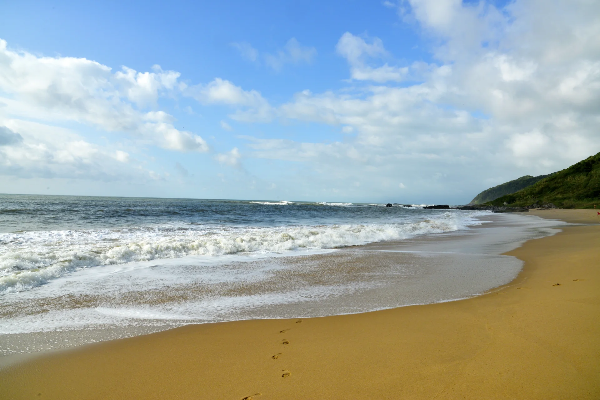 Vista aérea da Praia Vermelha, em Penha, com areia, mata e mar aberto