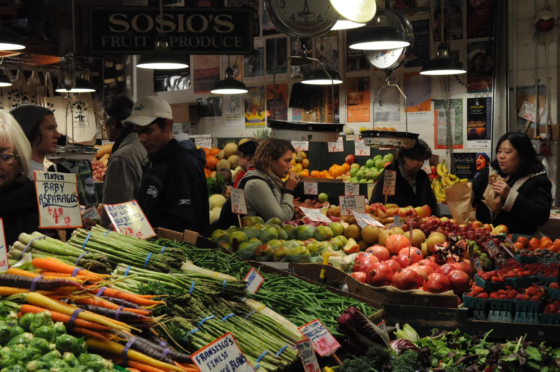 Frutas, verduras e clientes diante de uma banca de produtos no Pike Place Market.