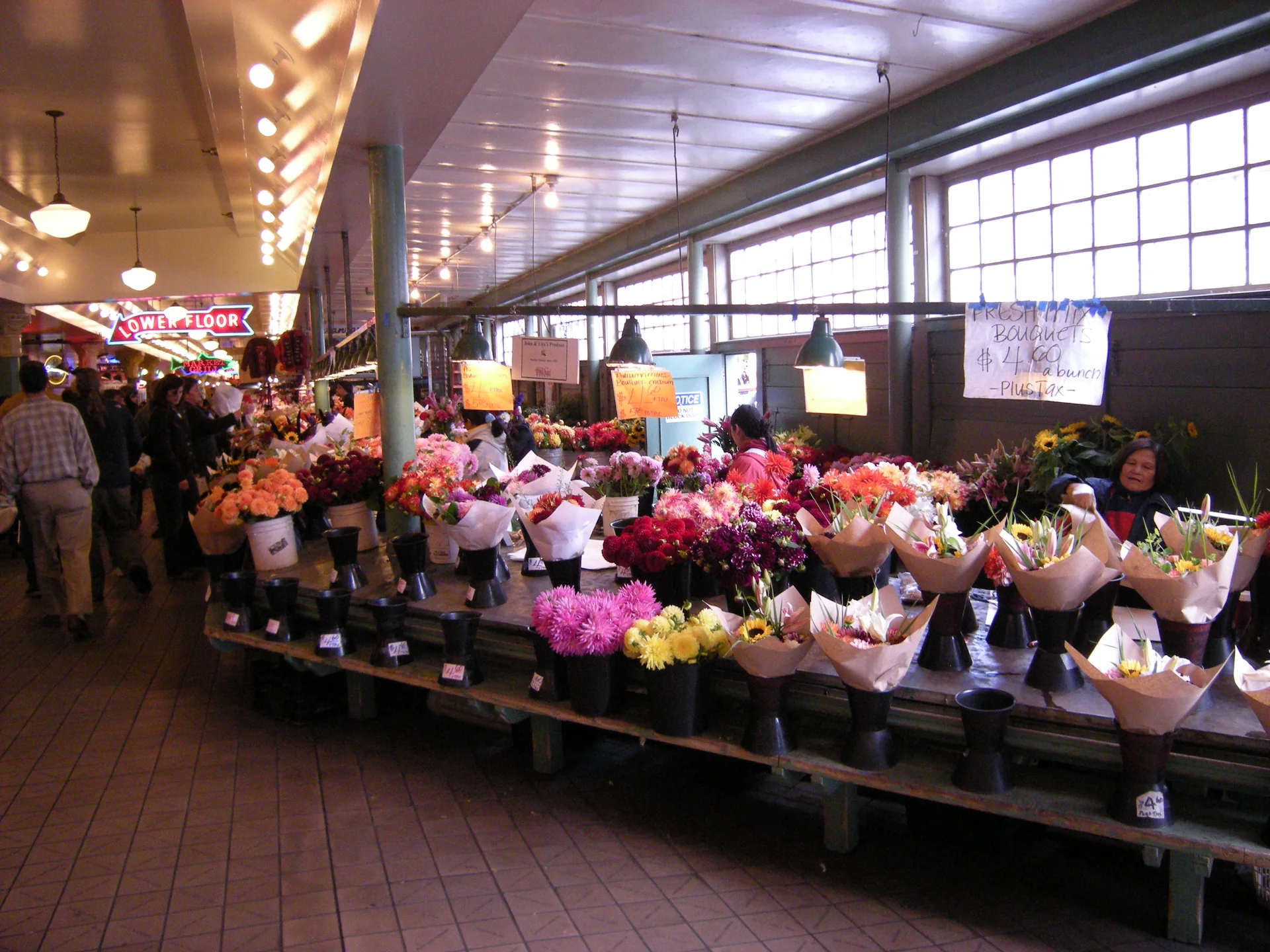 Bancas coloridas de flores com visitantes no Pike Place Market, em Seattle.