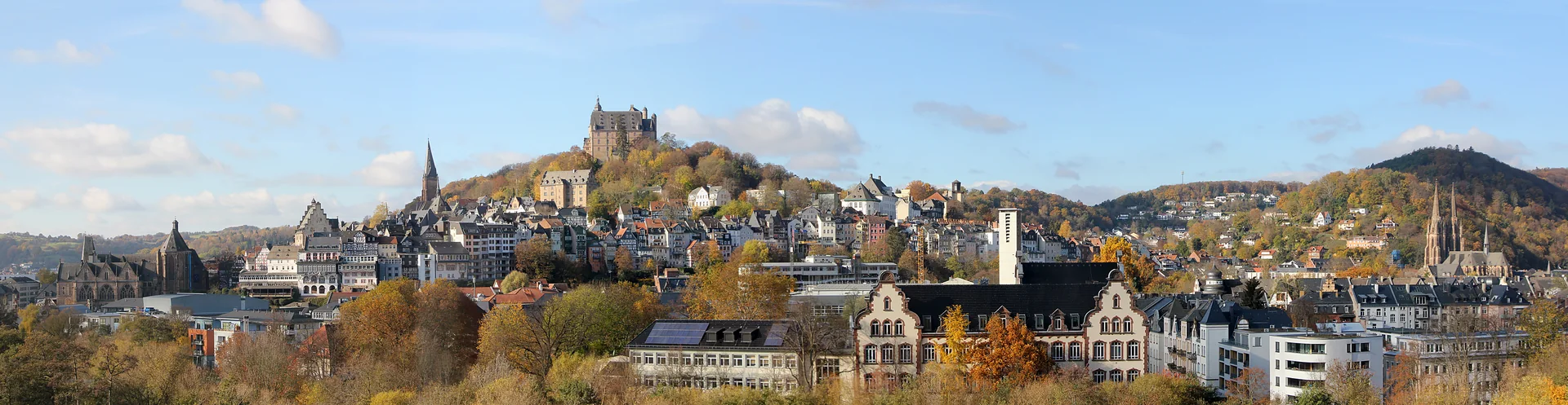 Panorama de outono de Marburg, com a cidade histórica e o castelo Landgrafenschloss entre colinas arborizadas.