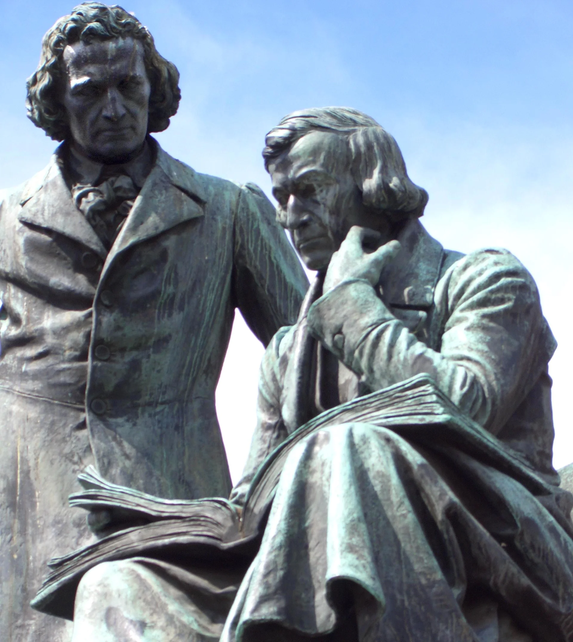 Estátua de Jacob e Wilhelm Grimm diante de edifícios da praça do mercado em Hanau.