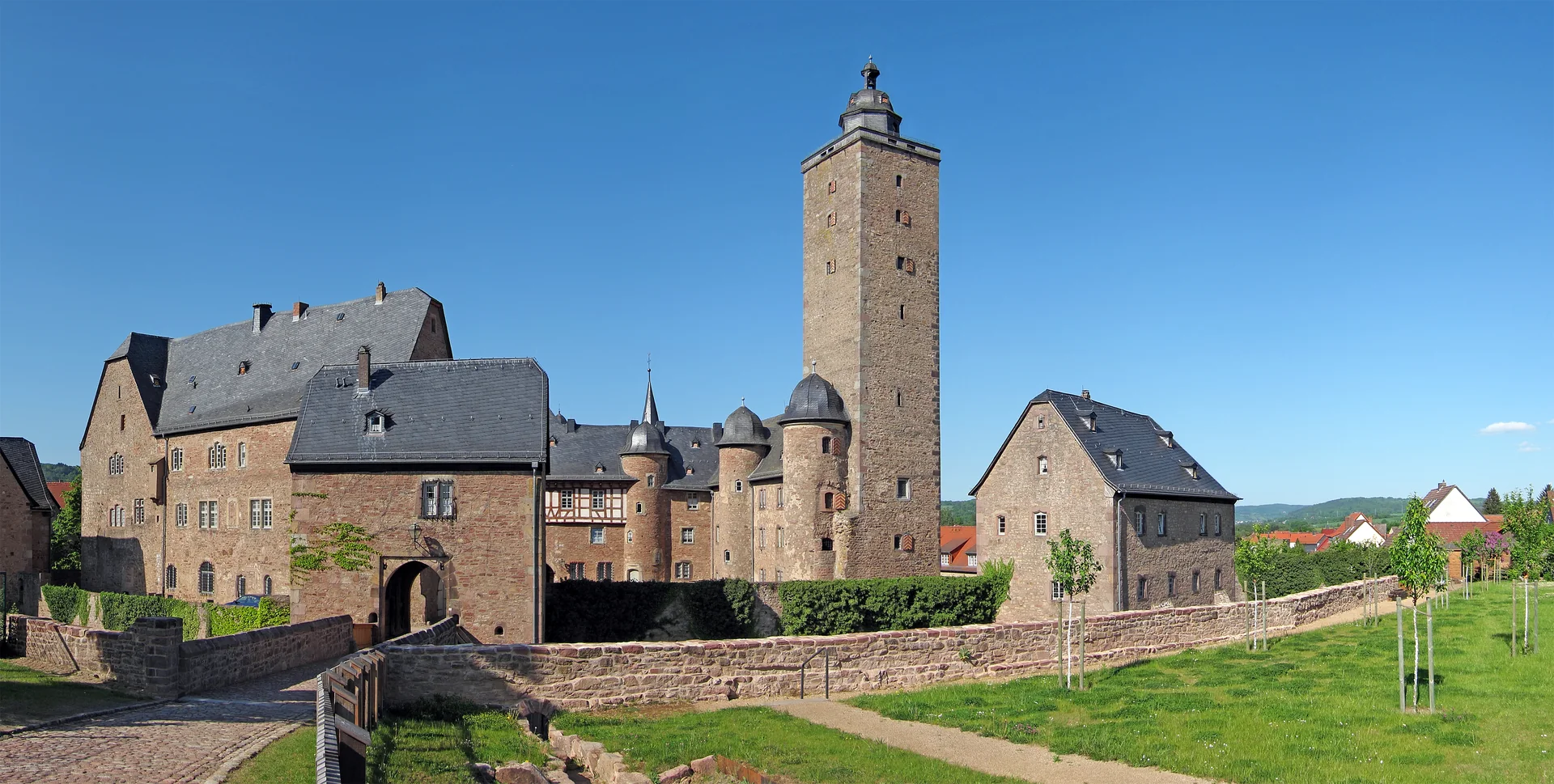 Vista externa do Castelo de Steinau sob céu azul, com muralhas e telhados históricos.