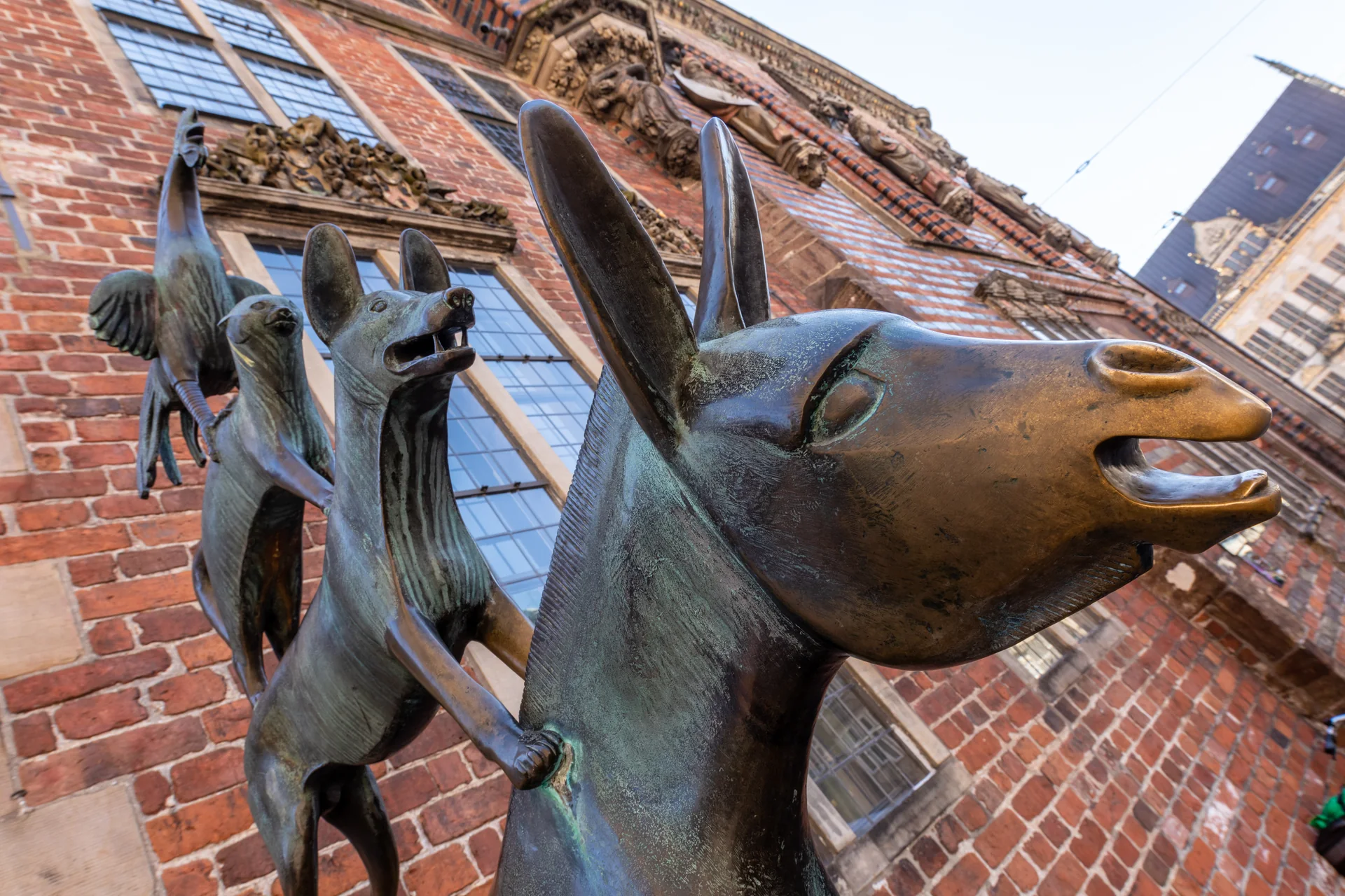 Escultura de bronze dos Músicos de Bremen ao lado da prefeitura histórica da cidade.