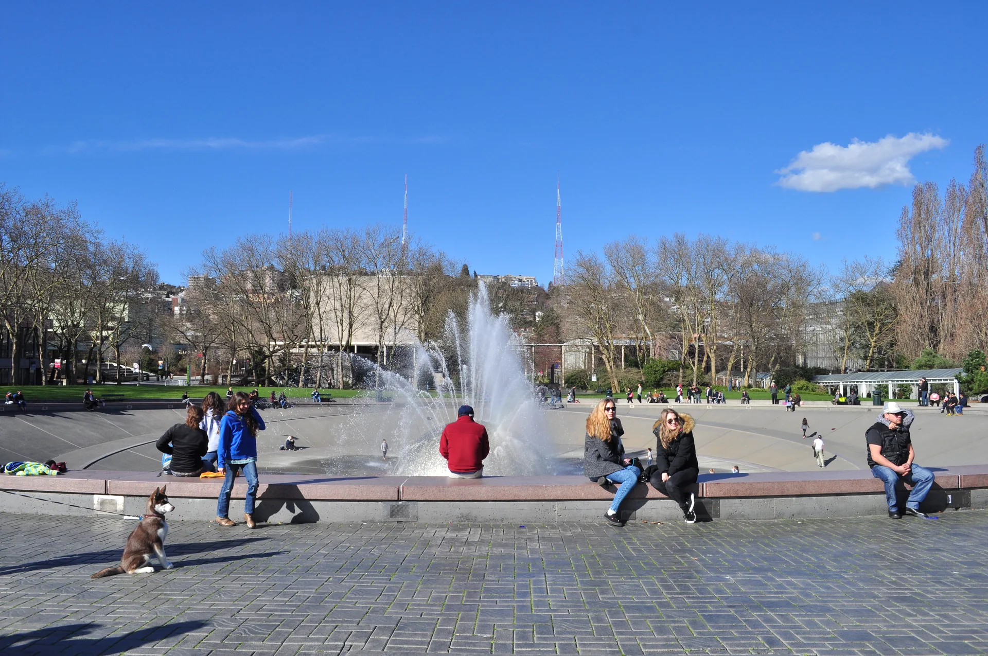 International Fountain com visitantes no Seattle Center em dia claro, vista voltada para Queen Anne Hill.