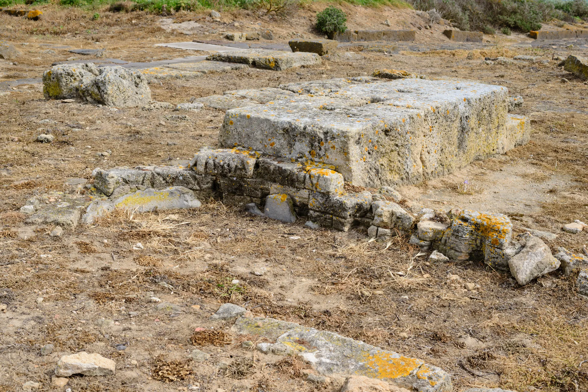 Muro de pedra e ruínas arqueológicas de Tharros sob céu azul