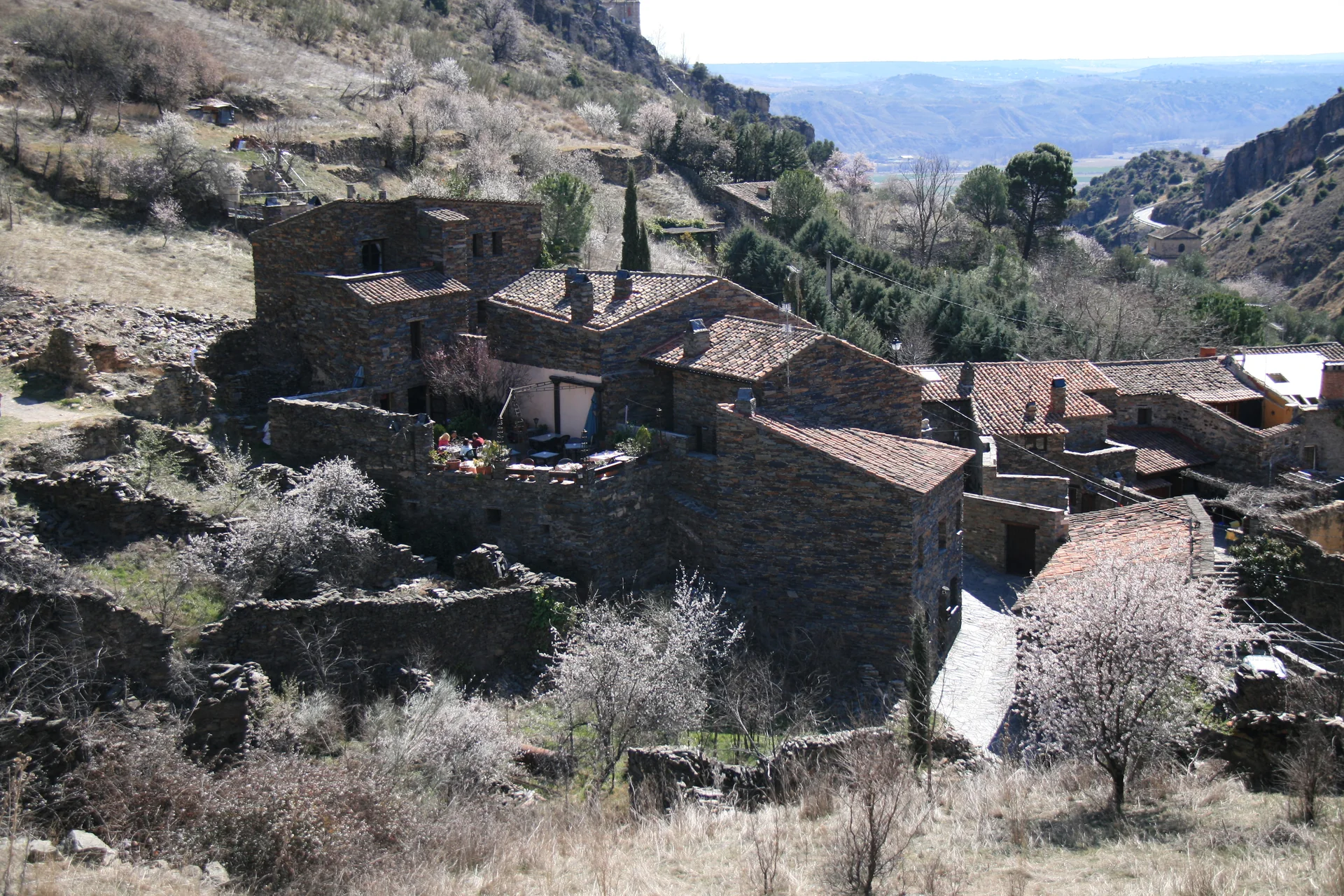 Casas de pedra escura e telhados de ardósia de Patones de Arriba em uma encosta.