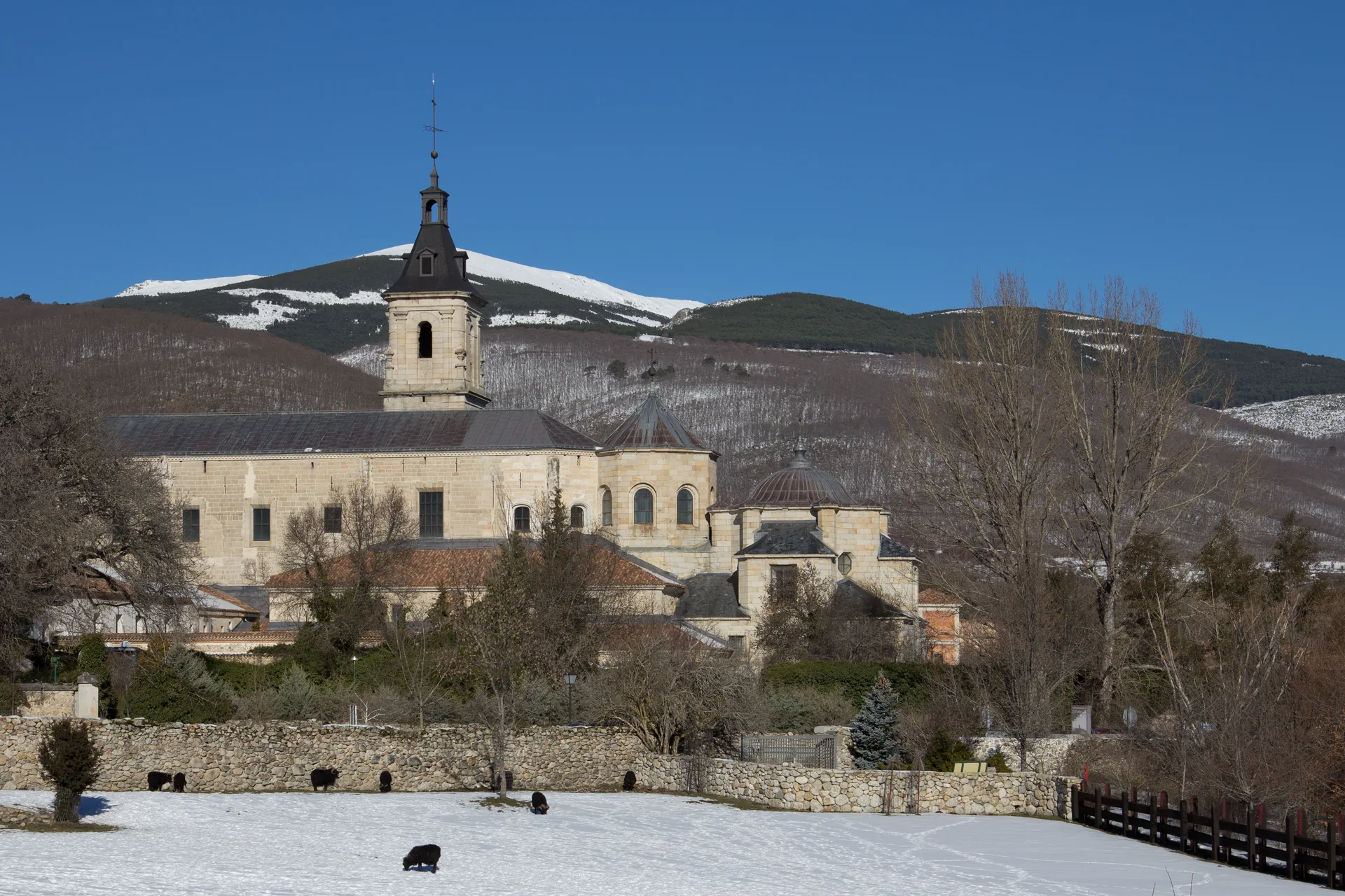 Fachada e telhados do Mosteiro de Santa María de El Paular, em Rascafría, diante de árvores.