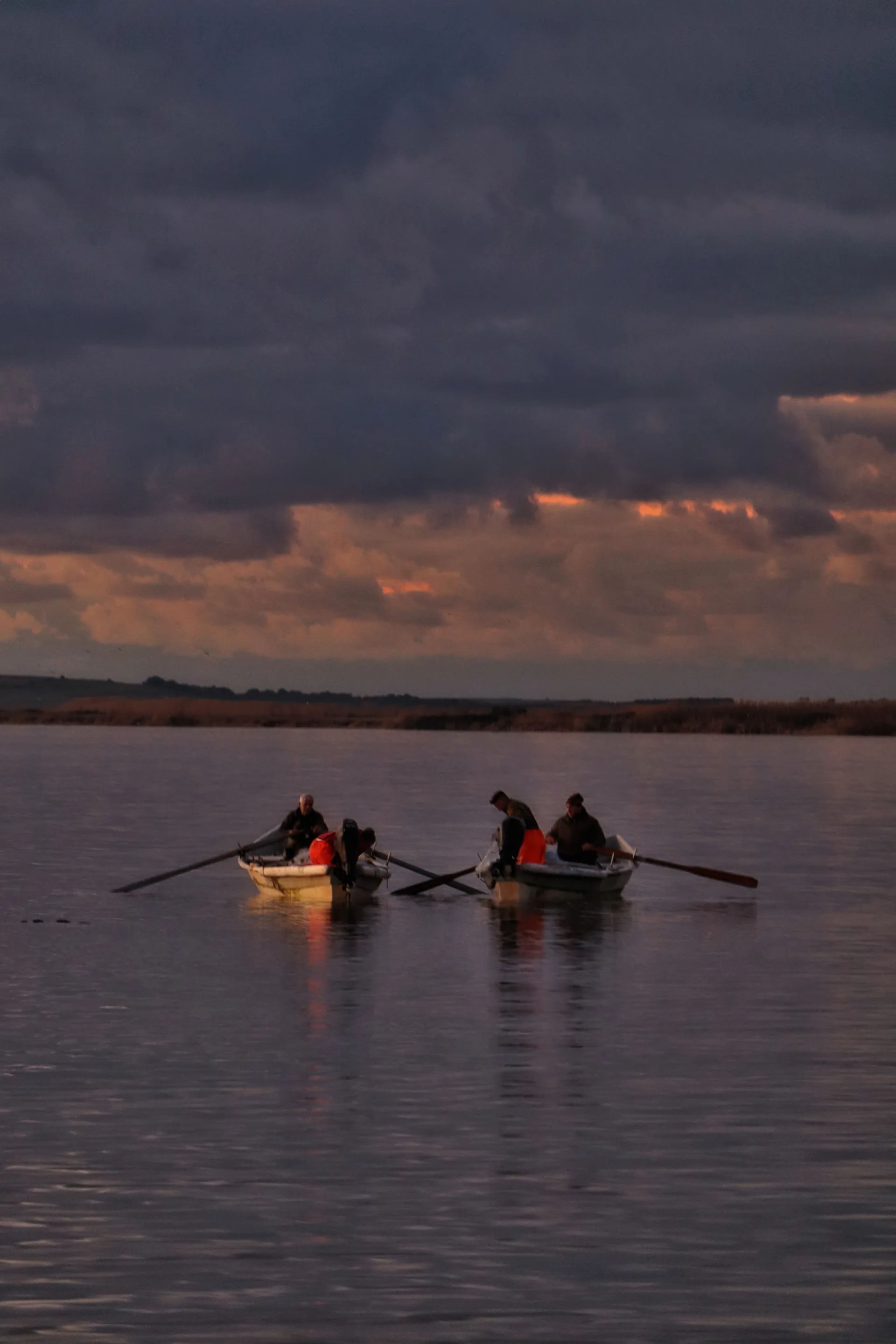 Dois pescadores em uma pequena embarcação sobre as águas da lagoa de Cabras, na Sardenha.