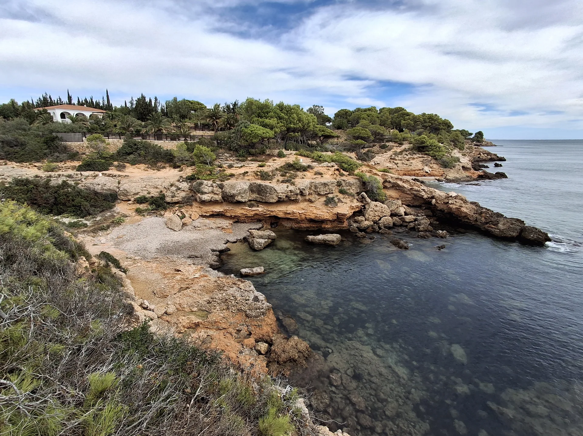 Enseada rochosa da praia de l’Ambrosia, em L’Ametlla de Mar, com pinheiros junto ao Mediterrâneo.