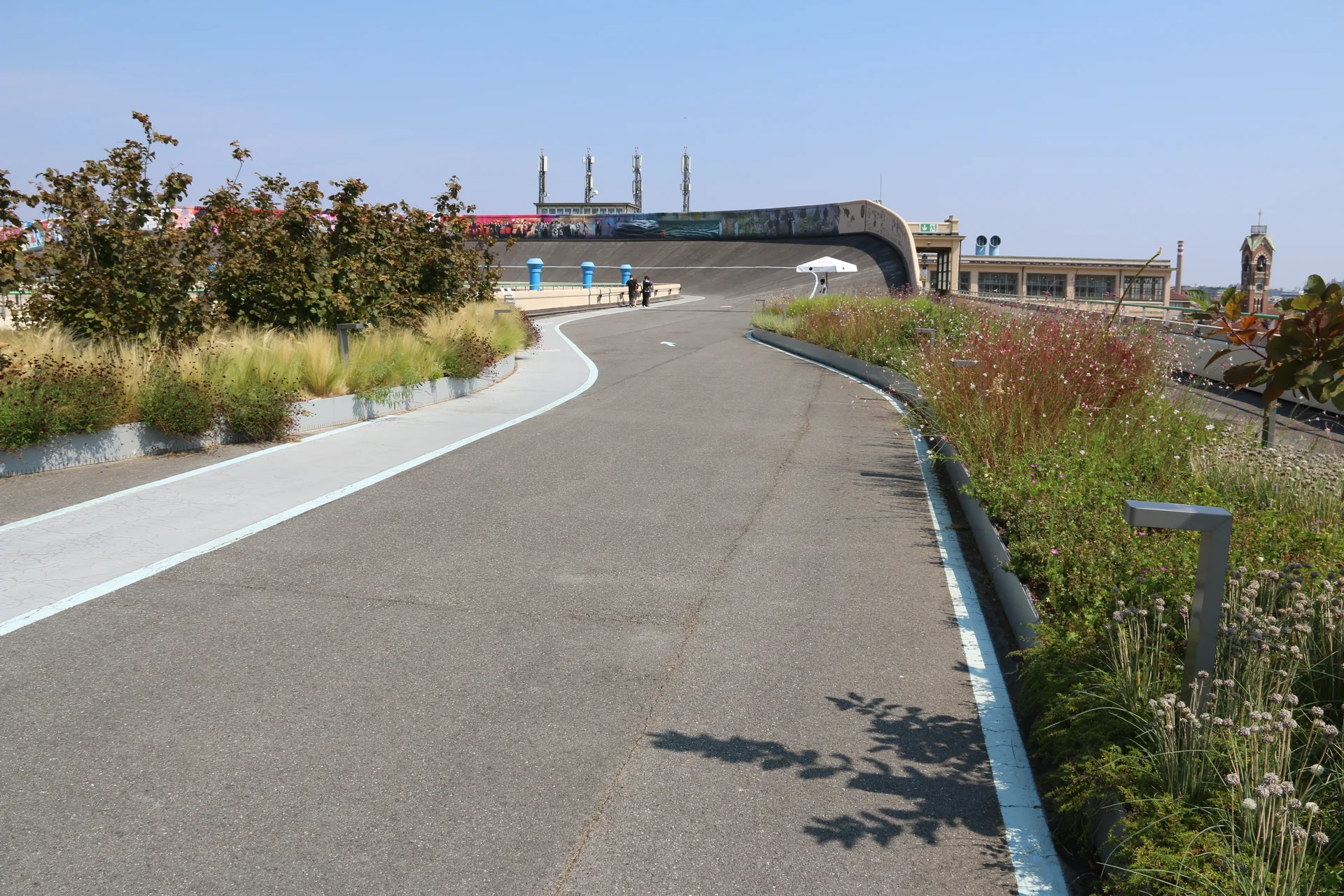 Curva da antiga pista de testes no terraço do Lingotto, com jardins e estruturas urbanas ao redor.