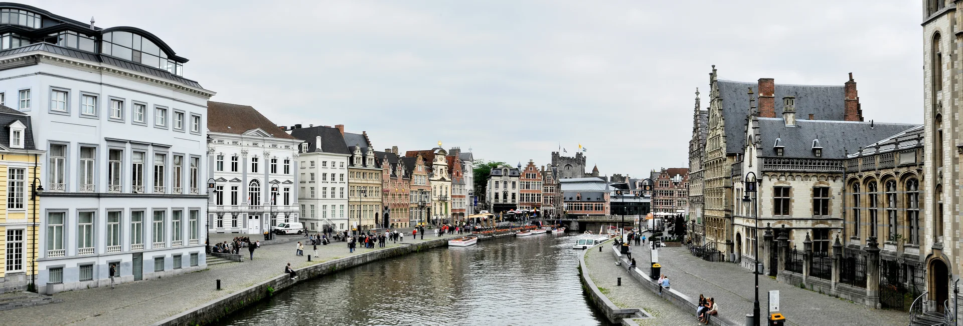 Panorama diurno do Graslei em Gante, visto da Ponte de São Miguel, com fachadas históricas, canal e torres ao fundo.