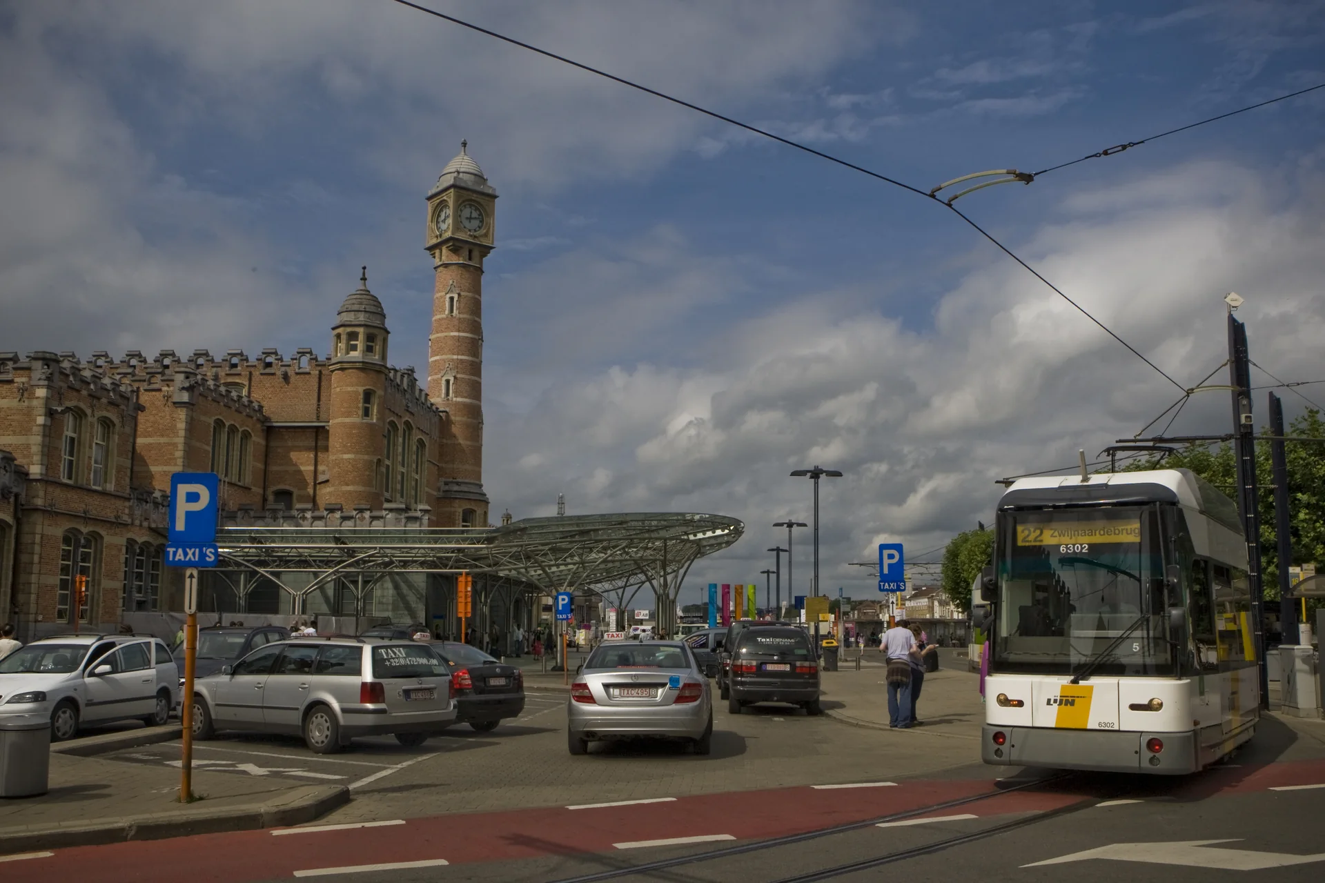 Fachada da estação Gent-Sint-Pieters em Gante, com bonde e circulação urbana em primeiro plano.