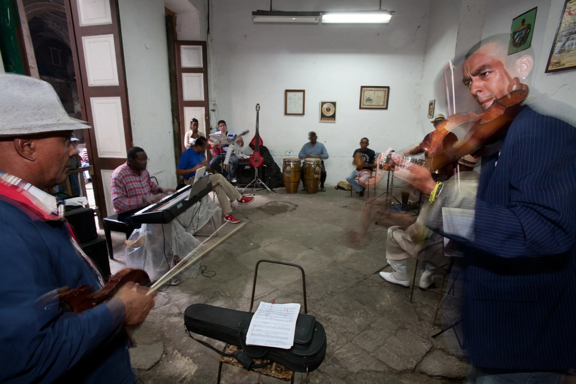 Músicos do Cuban All Stars ensaiam com violinos, teclado, baixo e percussão em um espaço cultural de Havana.