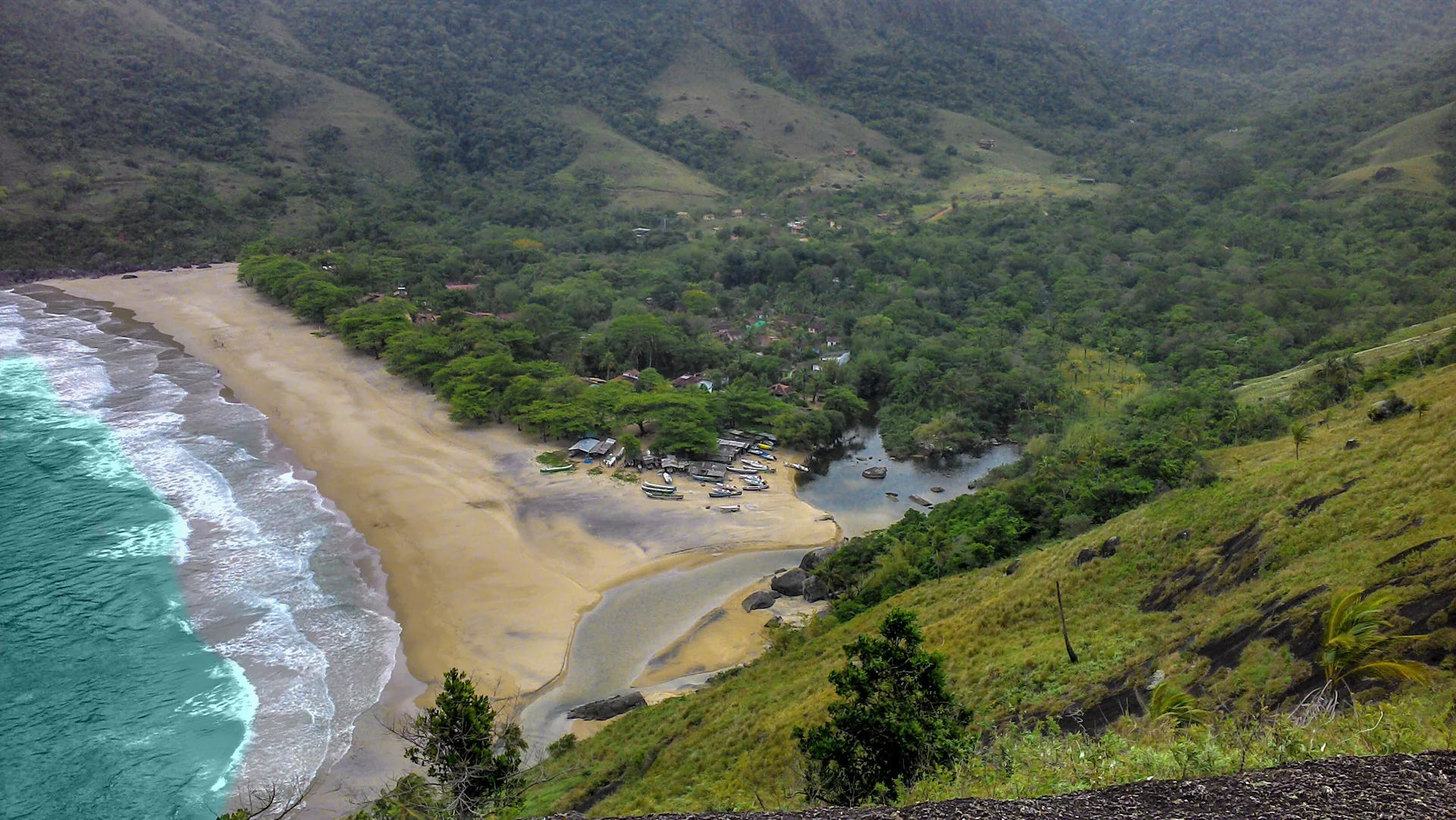 Vista aérea da Praia do Bonete, em Ilhabela, com a vila e barcos na faixa de areia.