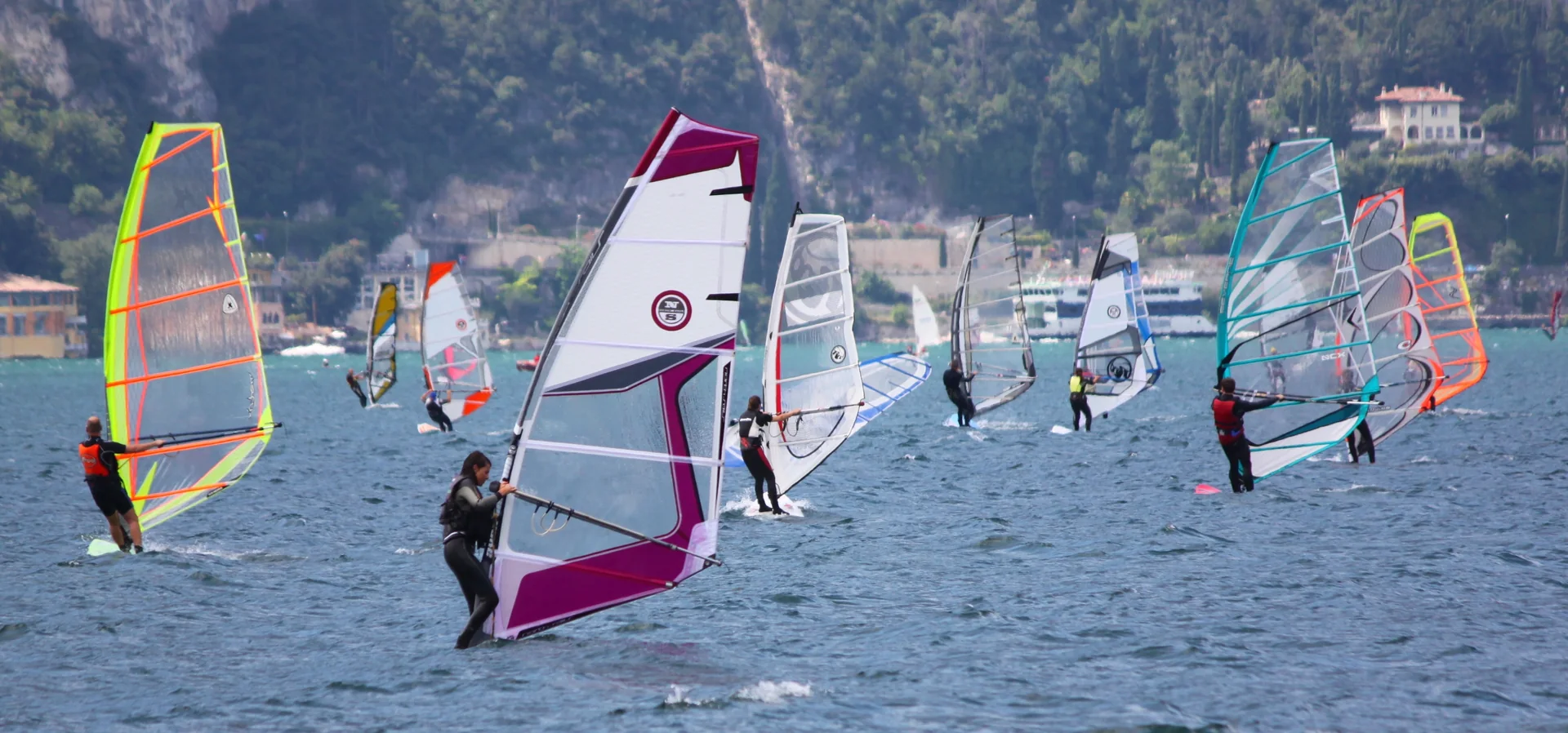 Praticante de windsurf no Lago di Garda, diante da margem montanhosa de Torbole.