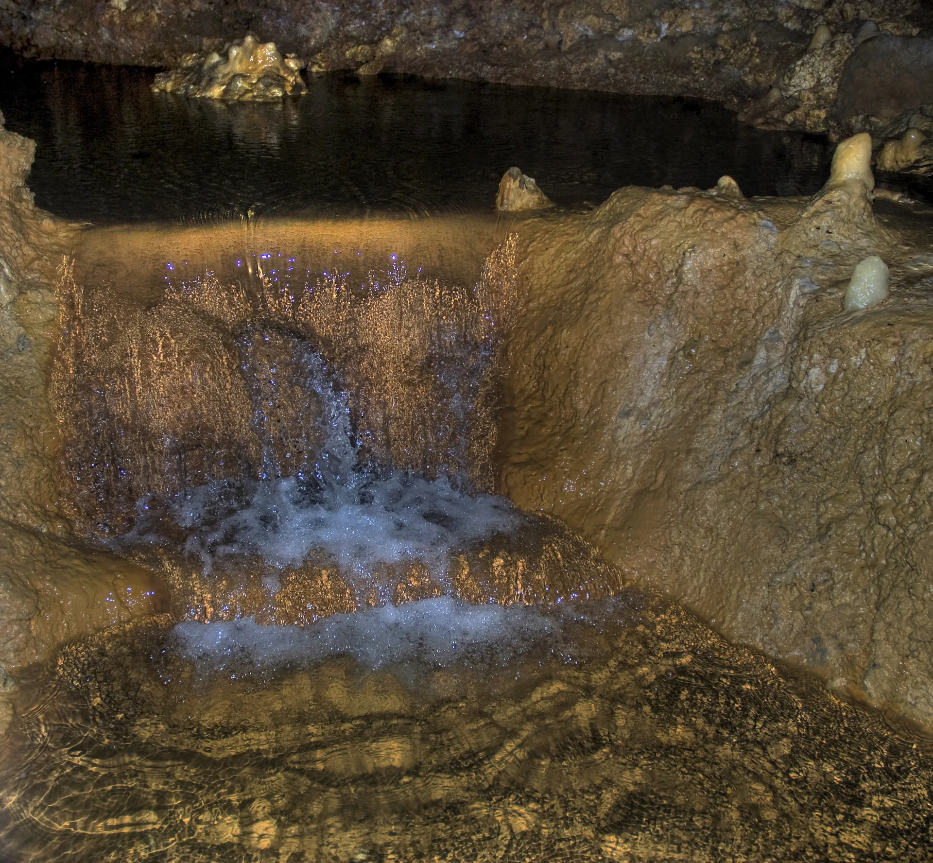 Água corrente e formações calcárias iluminadas no interior de Harrison’s Cave, em Barbados.