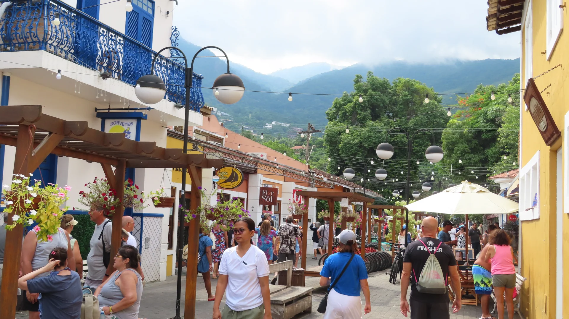 Vista diurna do Centro Histórico da Vila, em Ilhabela, com casario, vegetação e montanhas ao fundo.