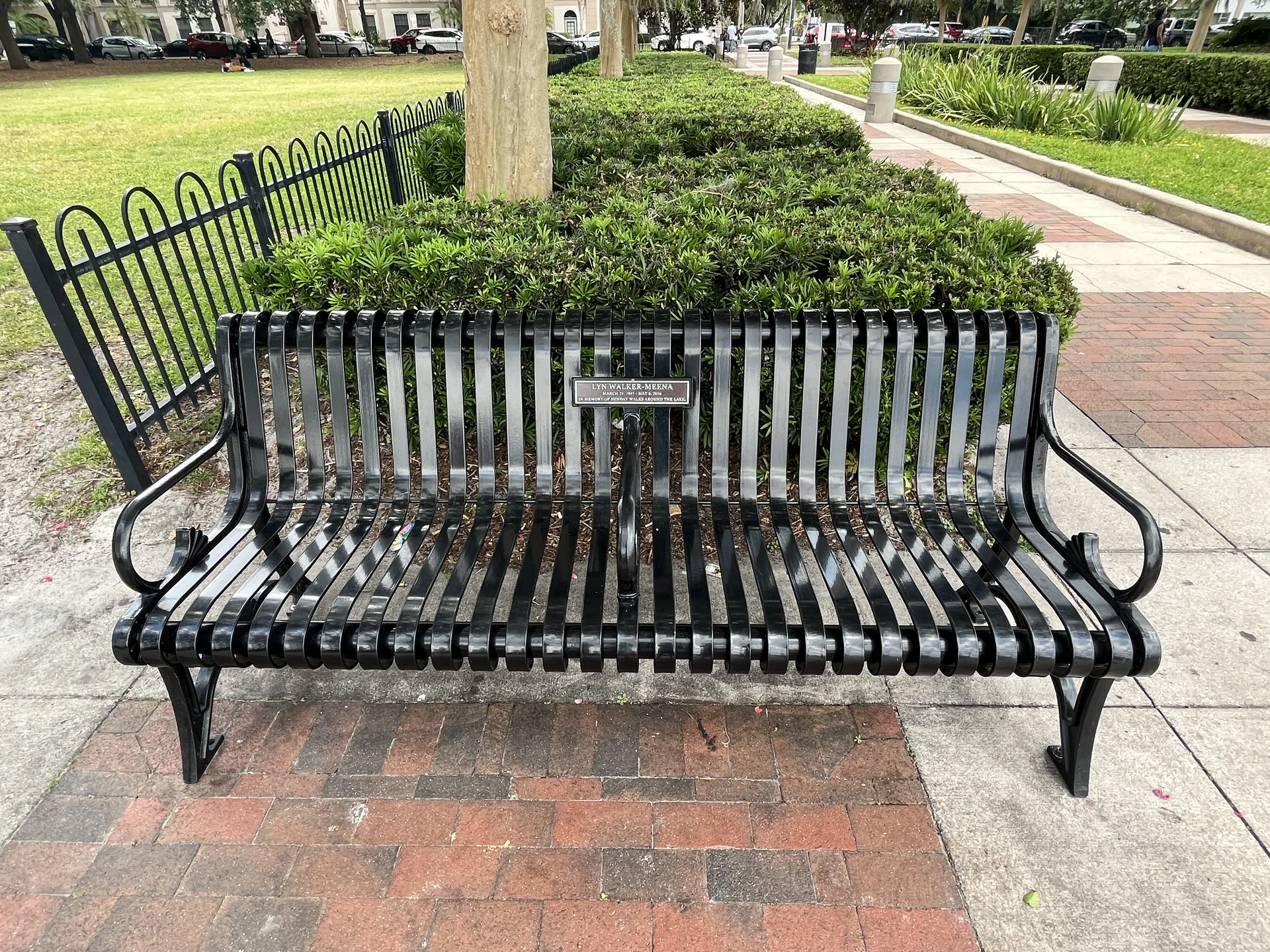 Banco vazio à sombra, junto ao caminho do Lake Eola Park, em Orlando.
