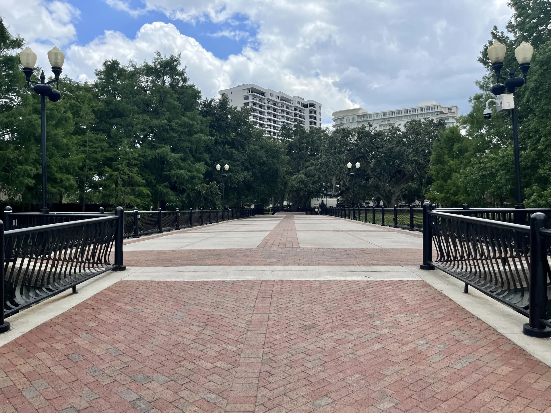 Passarela sobre a água no Lake Eola Park, em Orlando, com árvores e vegetação ao redor.
