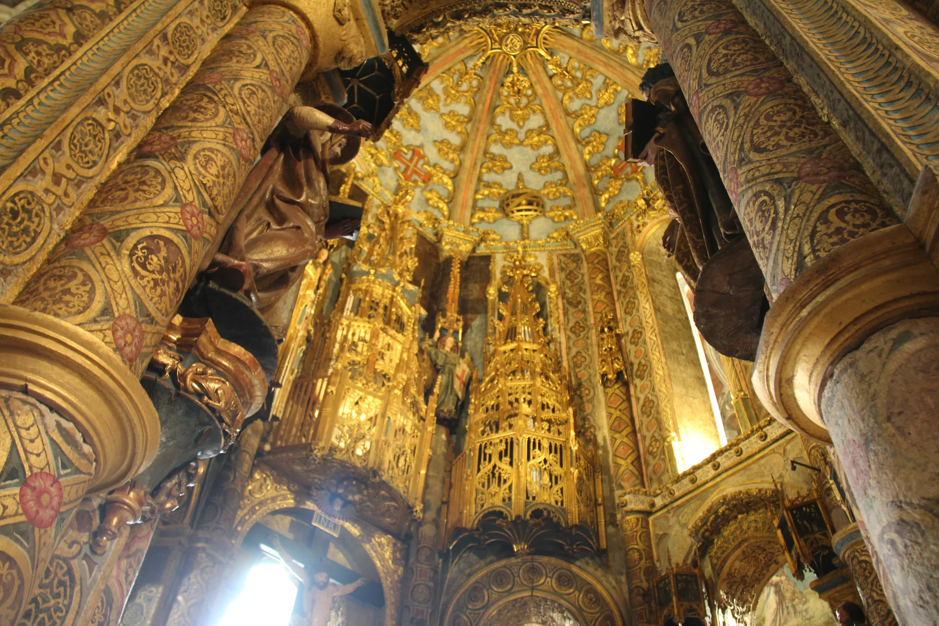 Interior da Charola em Tomar, com arcadas, pinturas e decoração histórica em torno do espaço central.