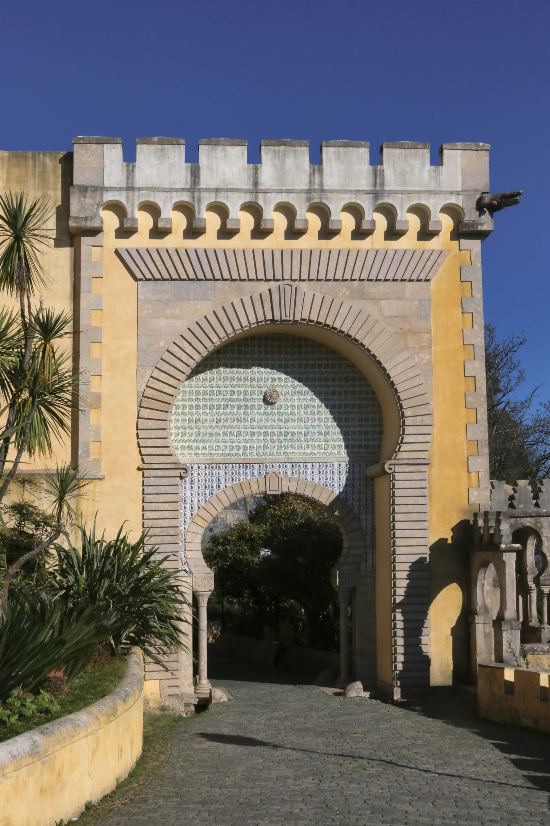 Portão de entrada amarelo e branco no exterior do Palácio Nacional da Pena, em Sintra.