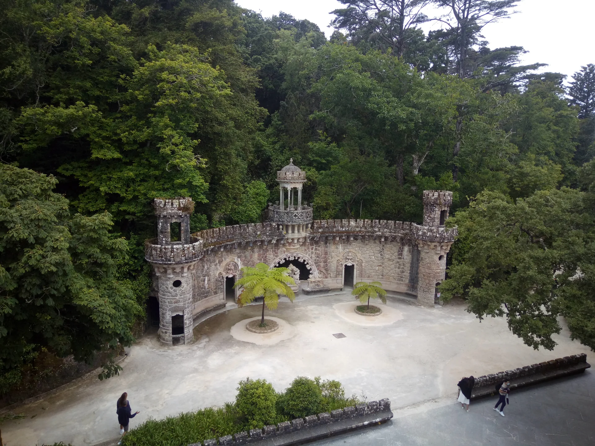 Vista elevada do Portal dos Guardiães, caminhos e vegetação da Quinta da Regaleira em Sintra.