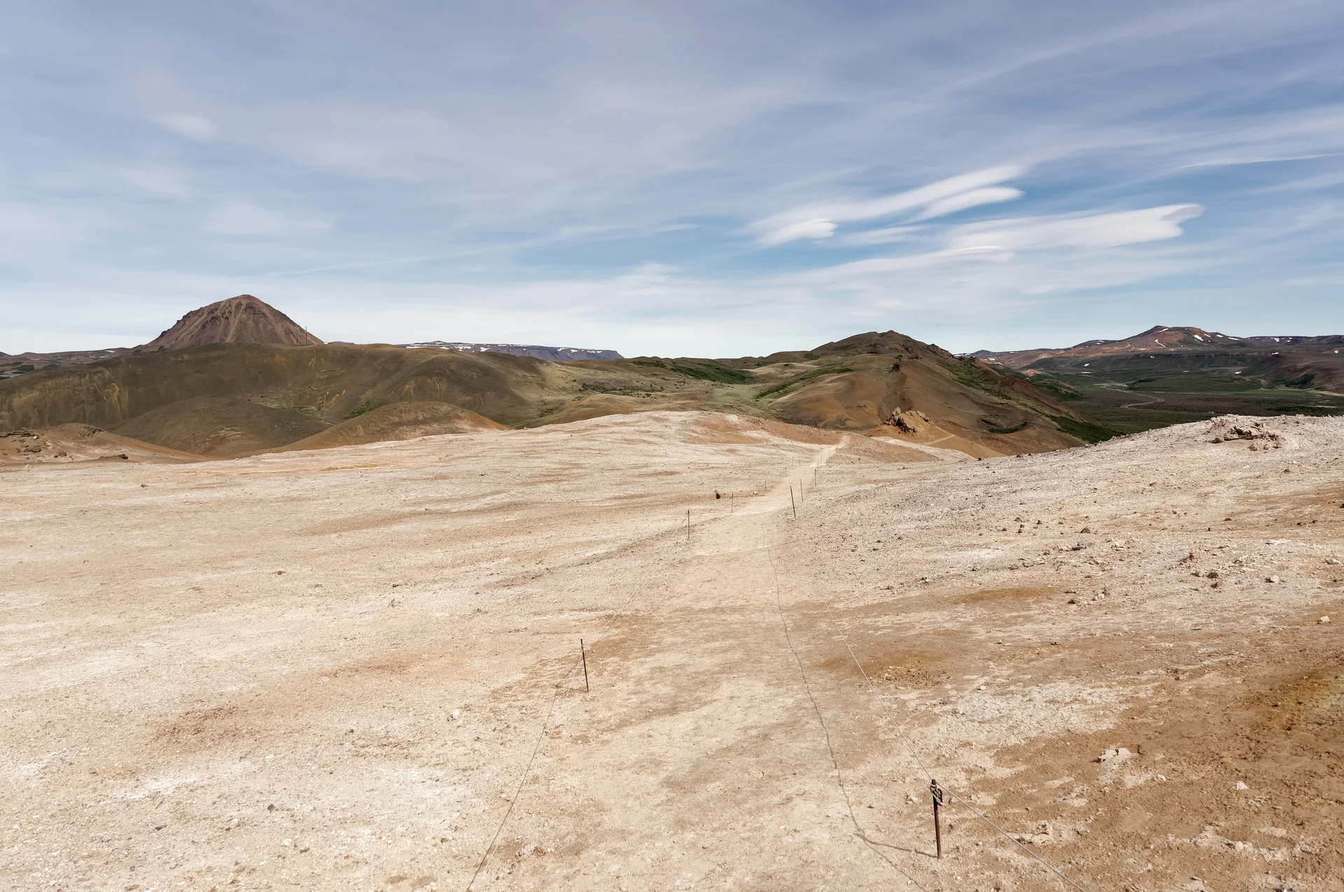 Trilha delimitada por cordas atravessa terreno geotérmico claro no monte Námafjall, Islândia.