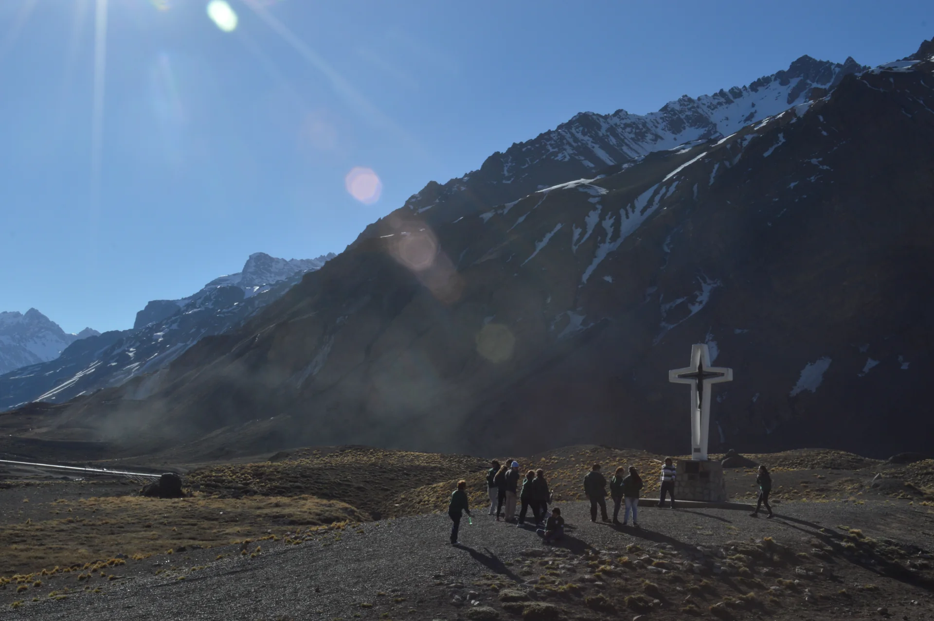 Entrada do Parque Provincial Aconcagua diante de encostas de montanha, com visitantes pequenos e não identificáveis no caminho.