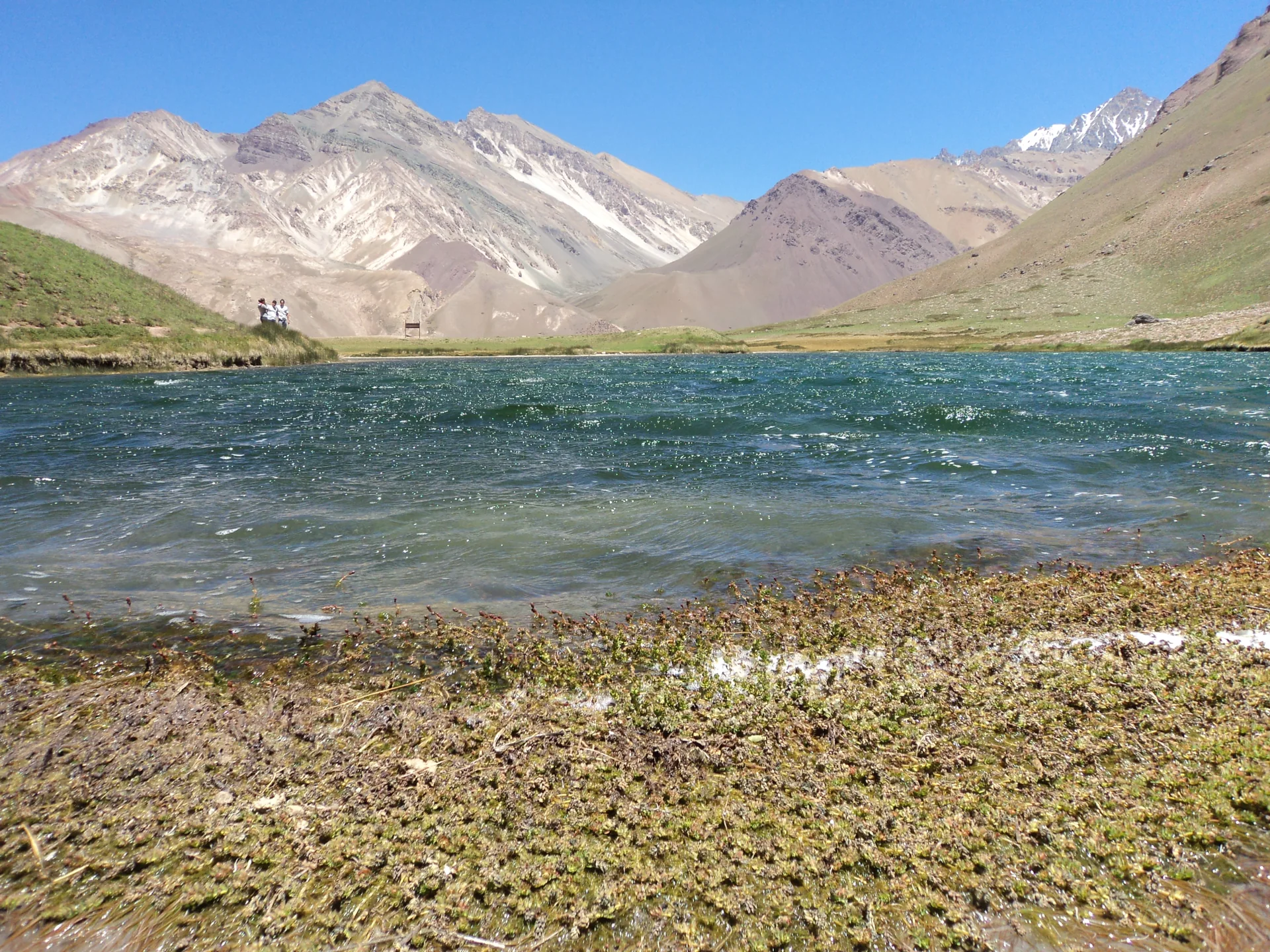 Laguna de Horcones entre encostas de alta montanha no Parque Provincial Aconcagua, sob céu com nuvens claras.