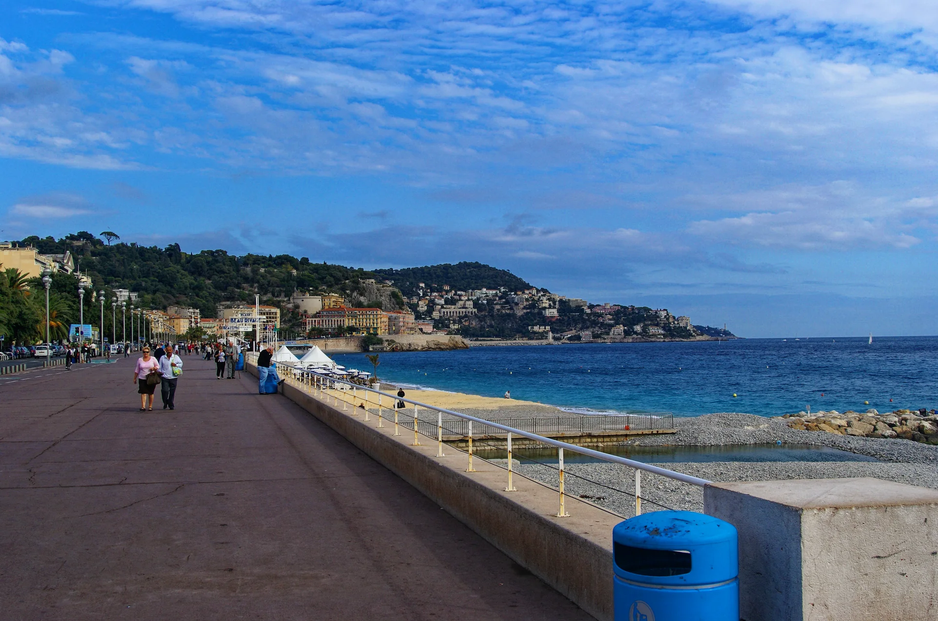 Promenade des Anglais em Nice, com o passeio, a borda construída, a Colline du Château e o Mediterrâneo.